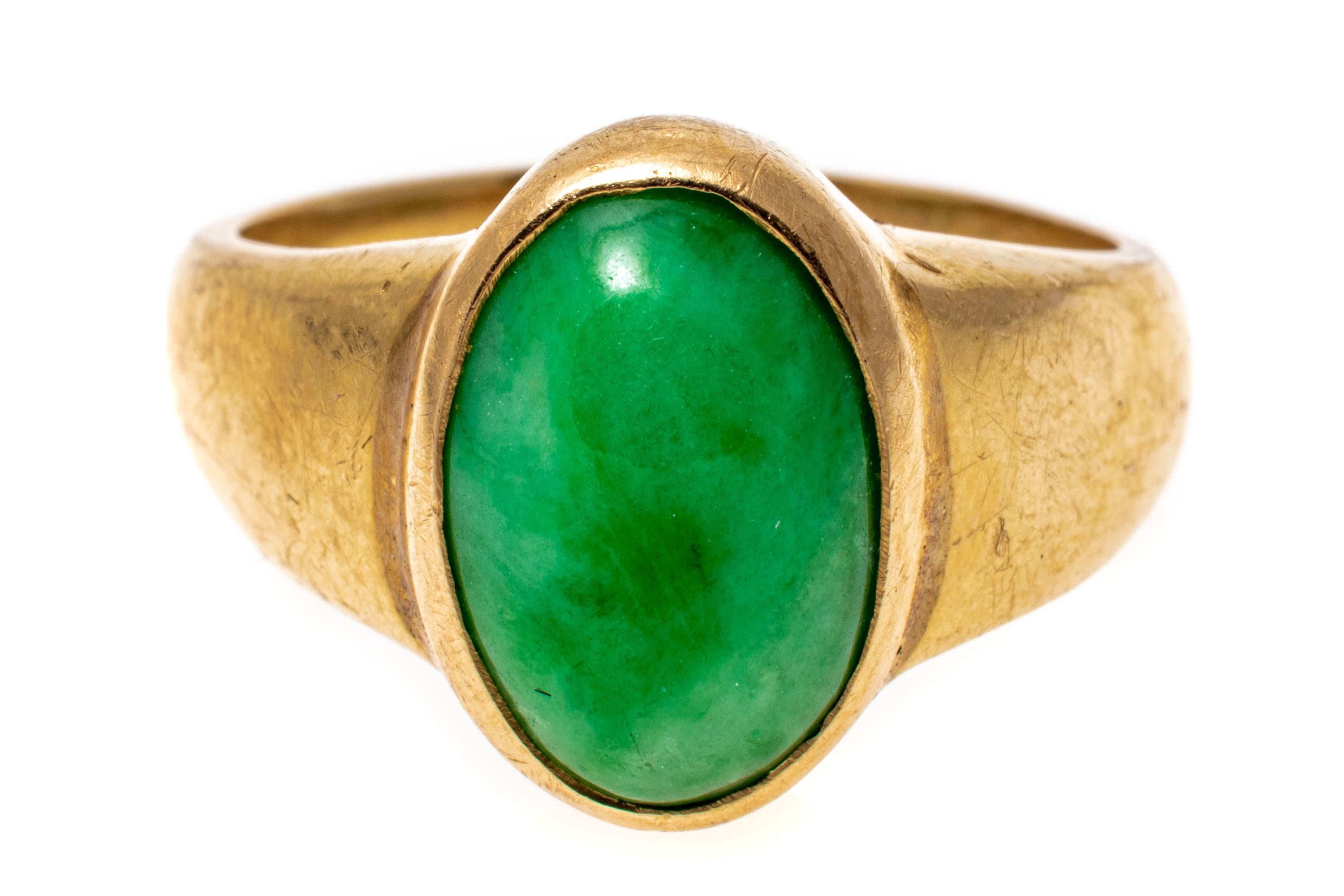 14k yellow gold ring. This simple yellow gold ring has an oval cabachon, green color jadeite jade center, bezel set and finished by wide, high polished shoulders.
Marks: 14k
Dimensions: 3/8