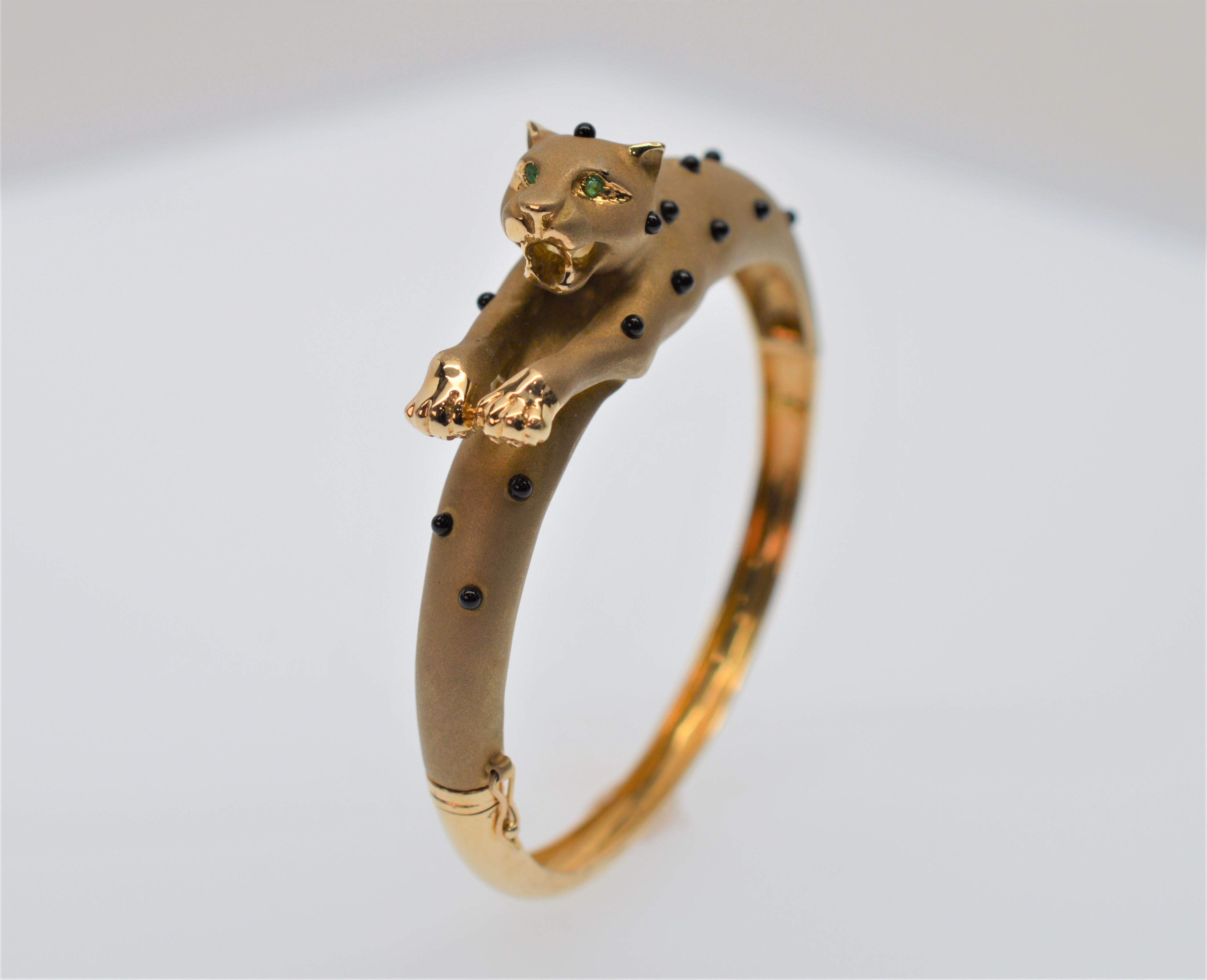 Unique and fun, this fourteen karat (14K) yellow gold leopard takes it all in stride to form this unusual bangle bracelet. Proudly sporting his black onyx spots, this brushed gold big cat is sure to garner attention bearing gold teeth and glaring