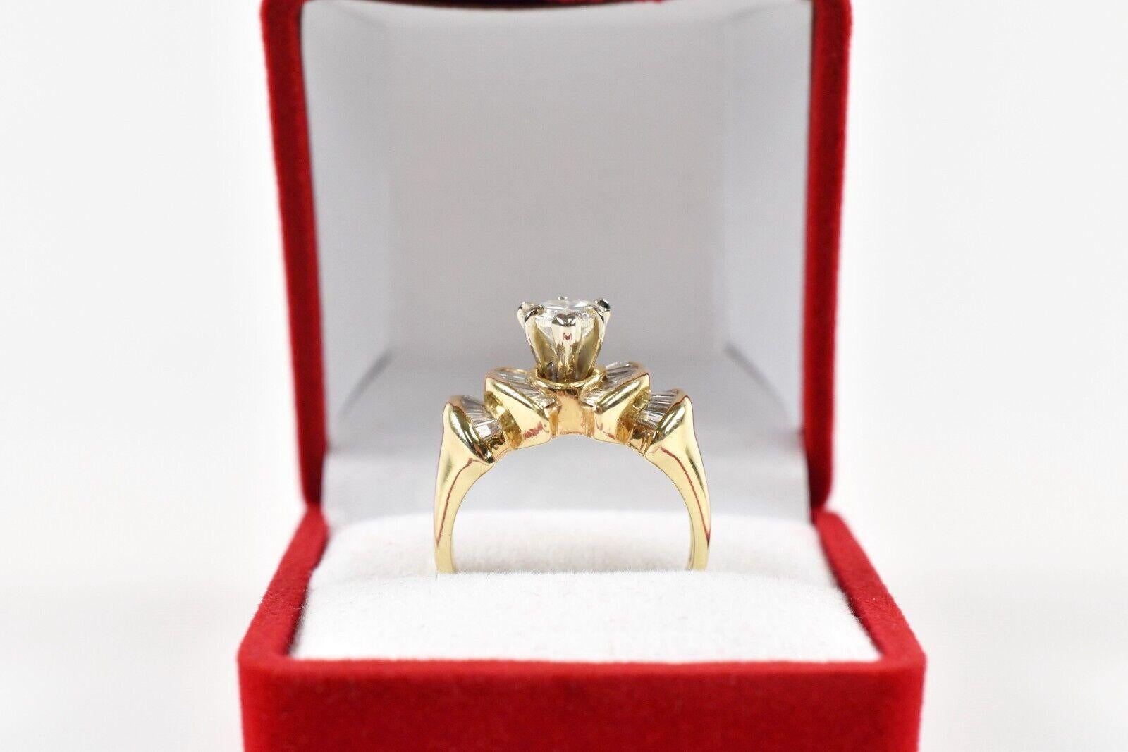 This stunning 14k yellow gold engagement ring showcases a brilliant pear-shaped diamond center stone set in a six-prong setting. Flanking the centerpiece are elegant fan-shaped arrangements of tapered baguette diamonds, each channel-set in a