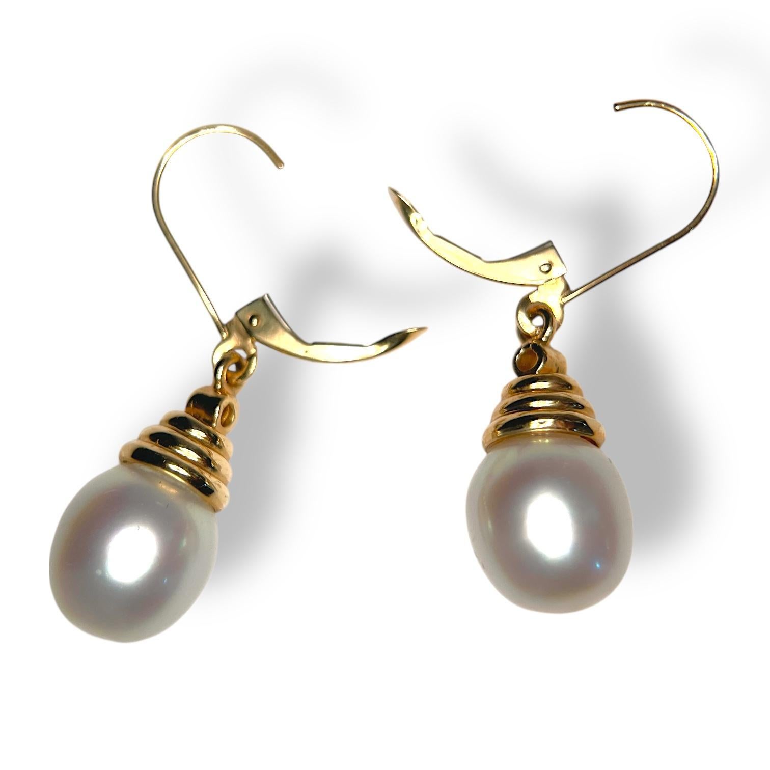 Eleva tu colección de joyas con estos exquisitos pendientes de perlas blancas, elegantemente suspendidos de ganchos chapados en oro amarillo de 14k. Cada pendiente presenta una perla lustrosa que irradia belleza atemporal, complementada con un