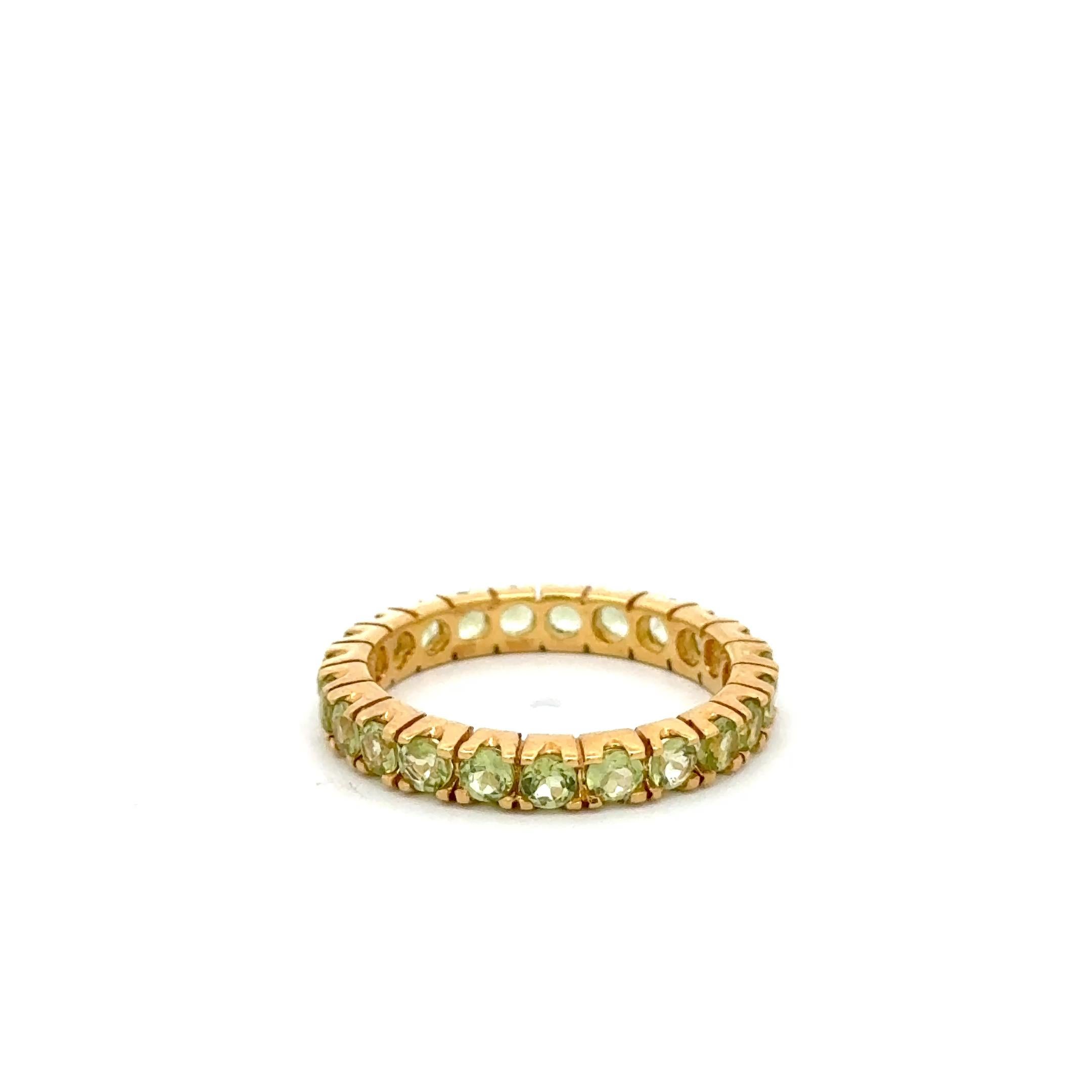 A timeless symbol of elegance and renewal, this stunning eternity band is crafted in glowing 14K yellow gold and features a continuous circle of vibrant natural peridot gemstones totaling approximately 1.25 carats. Each round-cut stone is