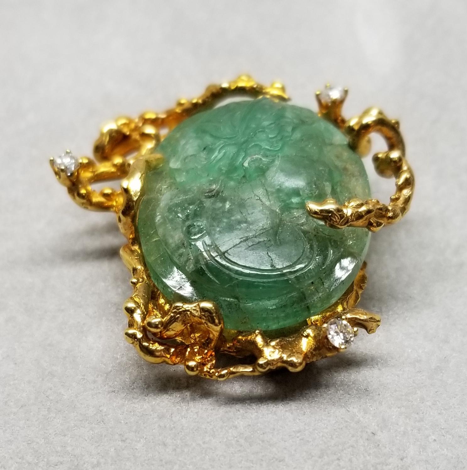 This piece of fine jewelry was designed and hand crafted by “Moshi” of New York, it was found in a vault from an estate sale and was never used.  14k yellow gold pin/pendant with a hand carved emerald weighing 29.41cts. with 3 round full cut