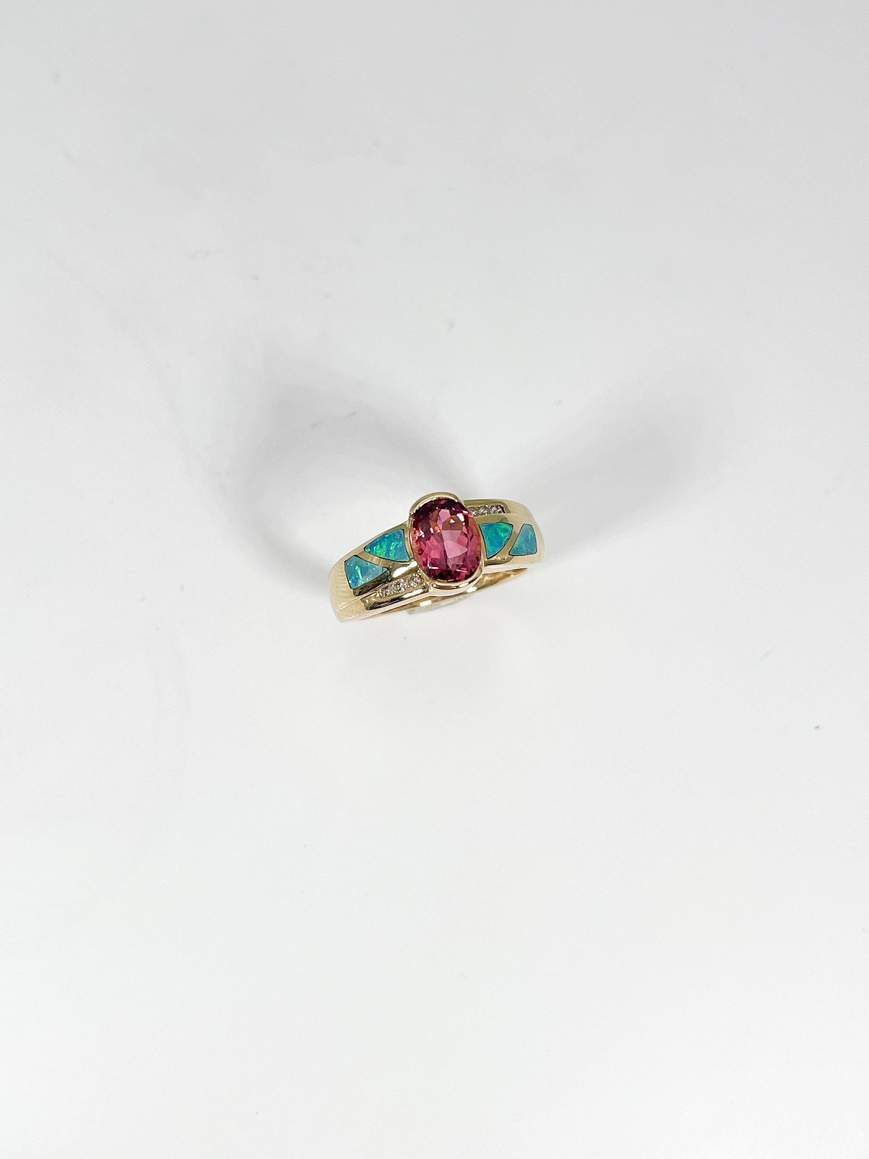 14k yellow gold fashion ring with a pink tourmaline center stone along with opal and diamond accents. The measurement of the center stone is 8.8 x 5.6 mm, and the ring has a total weight of 4.41 grams.
