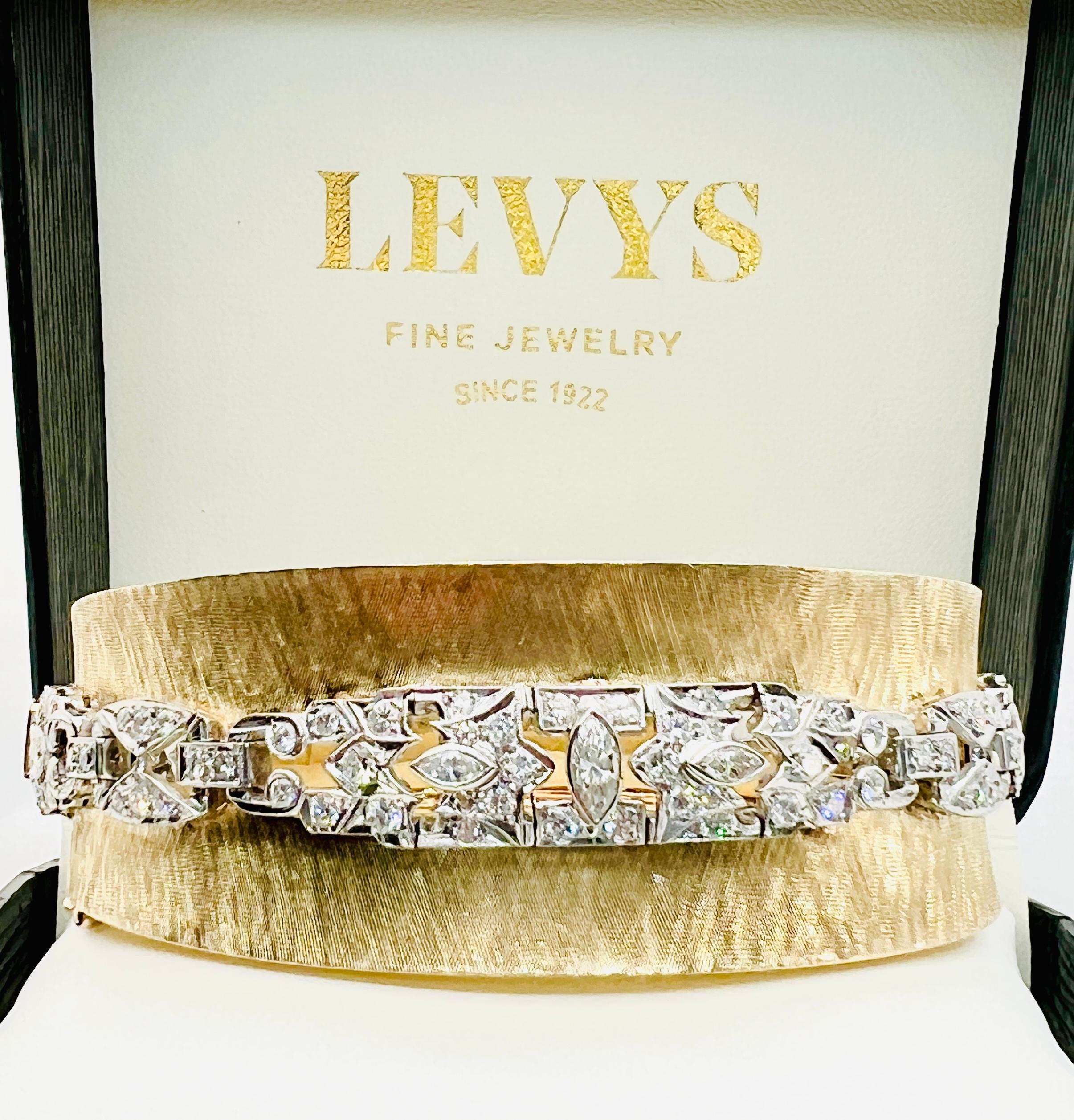 This is such a phenomenal bracelet! Made in 14K yellow gold with beautiful etching. The bangle has a slight concave shape to it. Along the mid section of the bangle is a stunning row of diamonds that are set in platinum. There are 118 round and 9