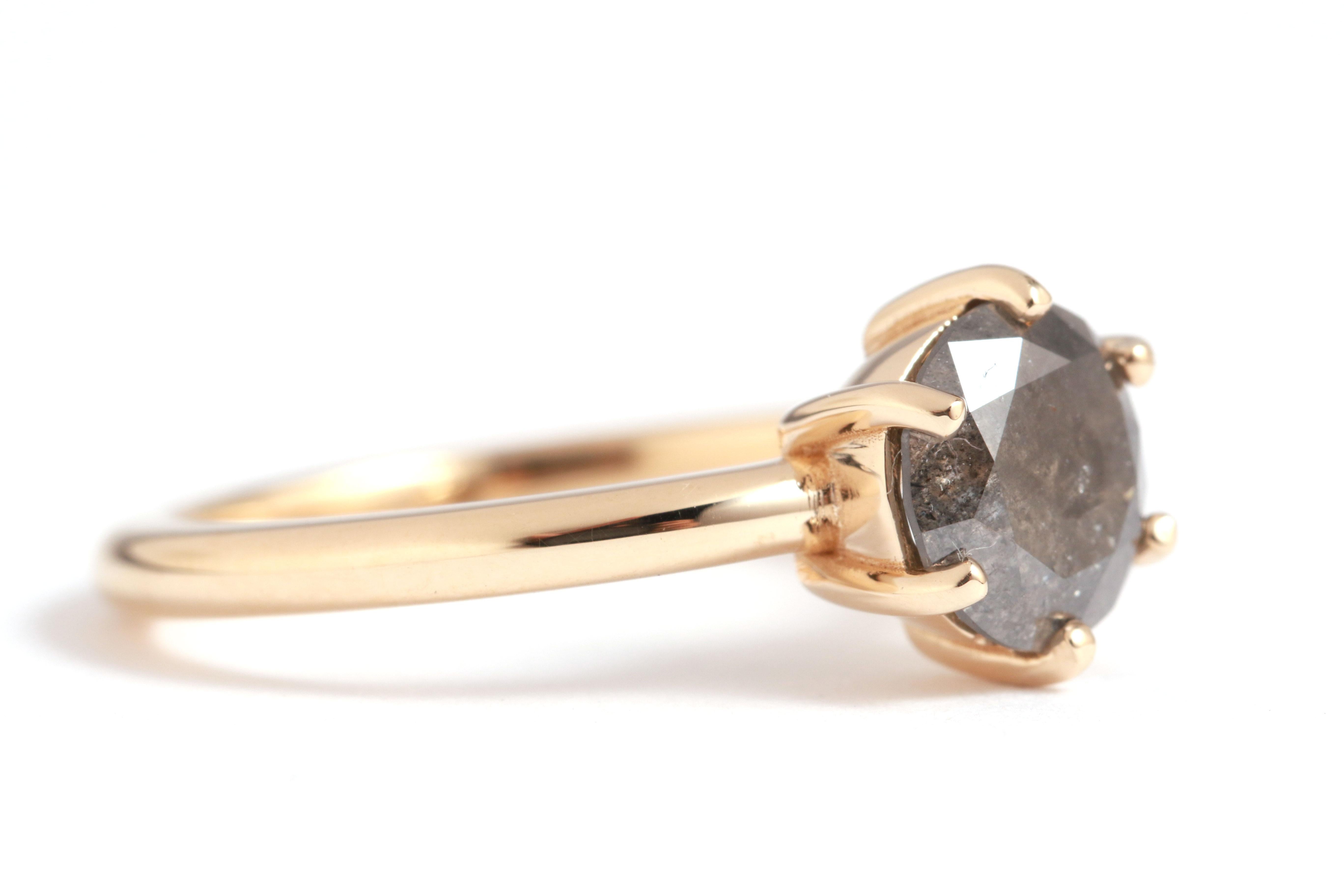 A deep peppery charcoal grey diamond with a classic brilliant cut, it set into a traditional basket prong setting. Completed with a smooth rounded gold band, for the perfect marriage of classic and edgy.

Stone:
Black and Grey Brilliant Cut Diamond,