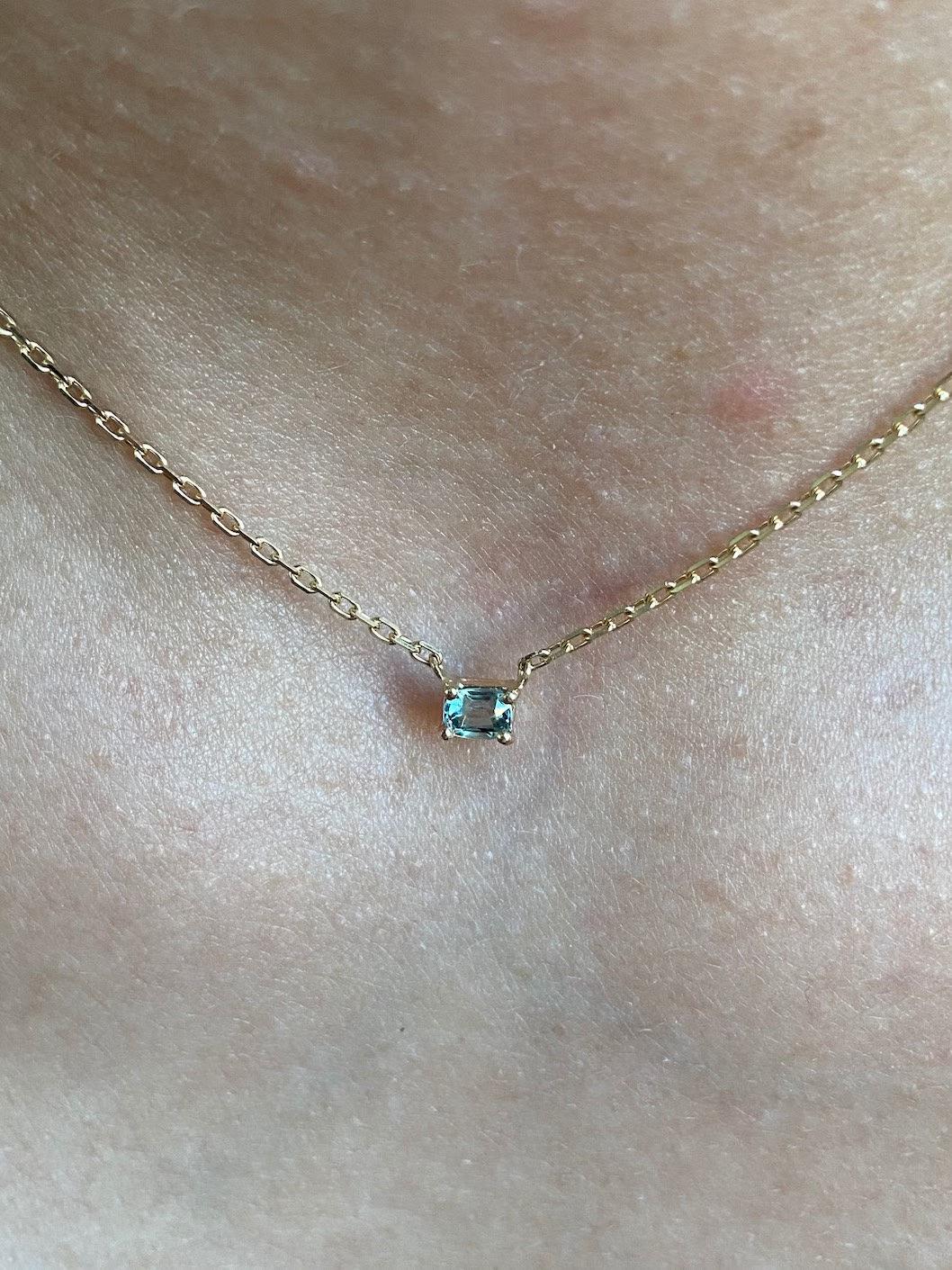 This unique turquoise sapphire necklace features a minimalist basket setting, highlighting the vibrant color of the sapphire. Set in yellow gold, the necklace is paired with a delicate cable chain.  

The sapphire weighs 0.30 carats, adding a subtle