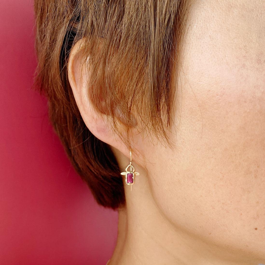 The 14k Yellow Gold Red Tourmaline Bull Ox Animal Earrings by Baubou are handcrafted in New York and feature a pinkish red 0.58 carat emerald cut tourmaline. The earrings measure approximately 10mm x 10.8mm with french wire. The logo is engraved on