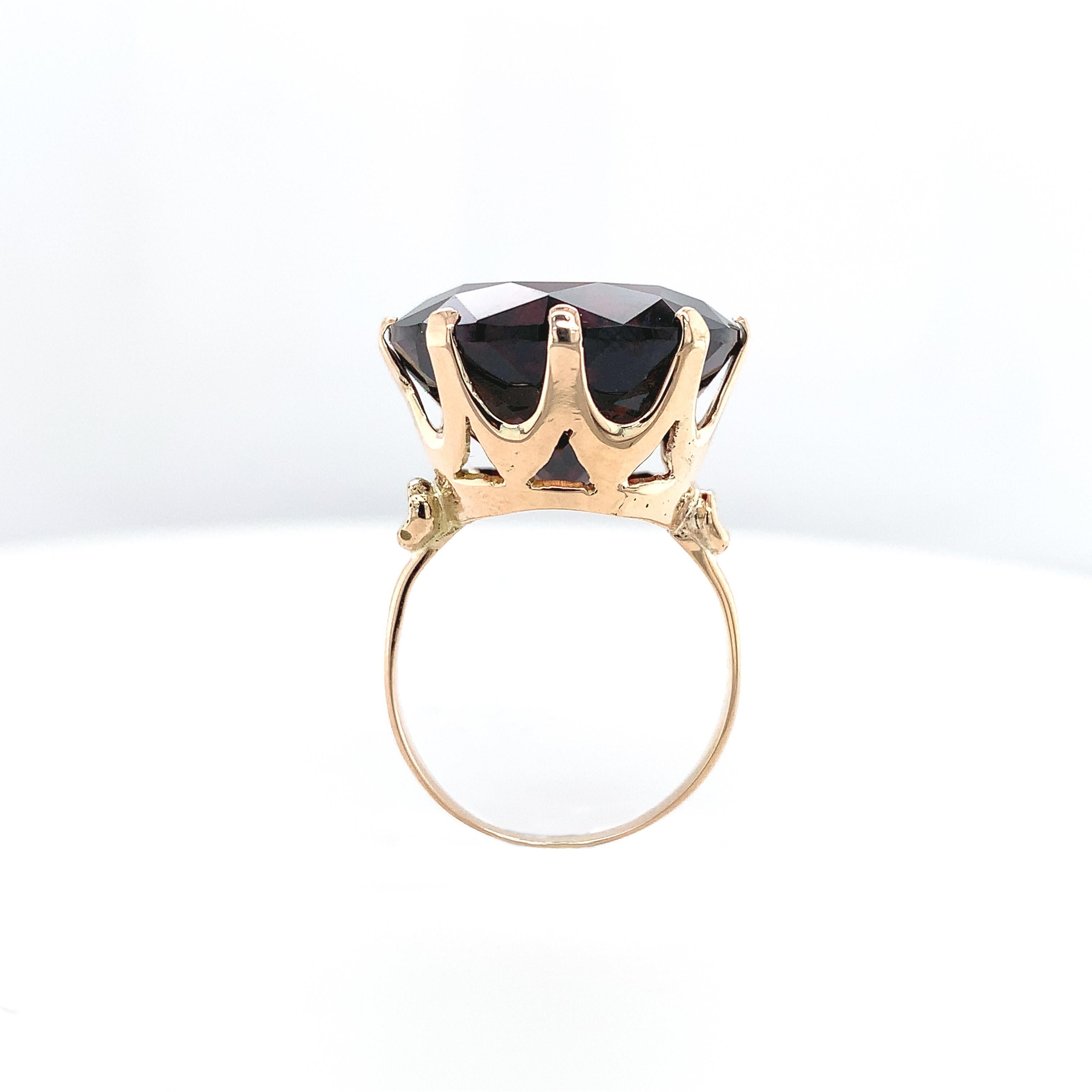 14K Yellow gold solitaire ring featuring a huge round garnet weighing 27.24 carats. The deep red garnet measures almost 18mm. The ring fits a size 7 finger and is easily sized. It weighs 5.35dwt and dates from the 1950's with all new prongs.