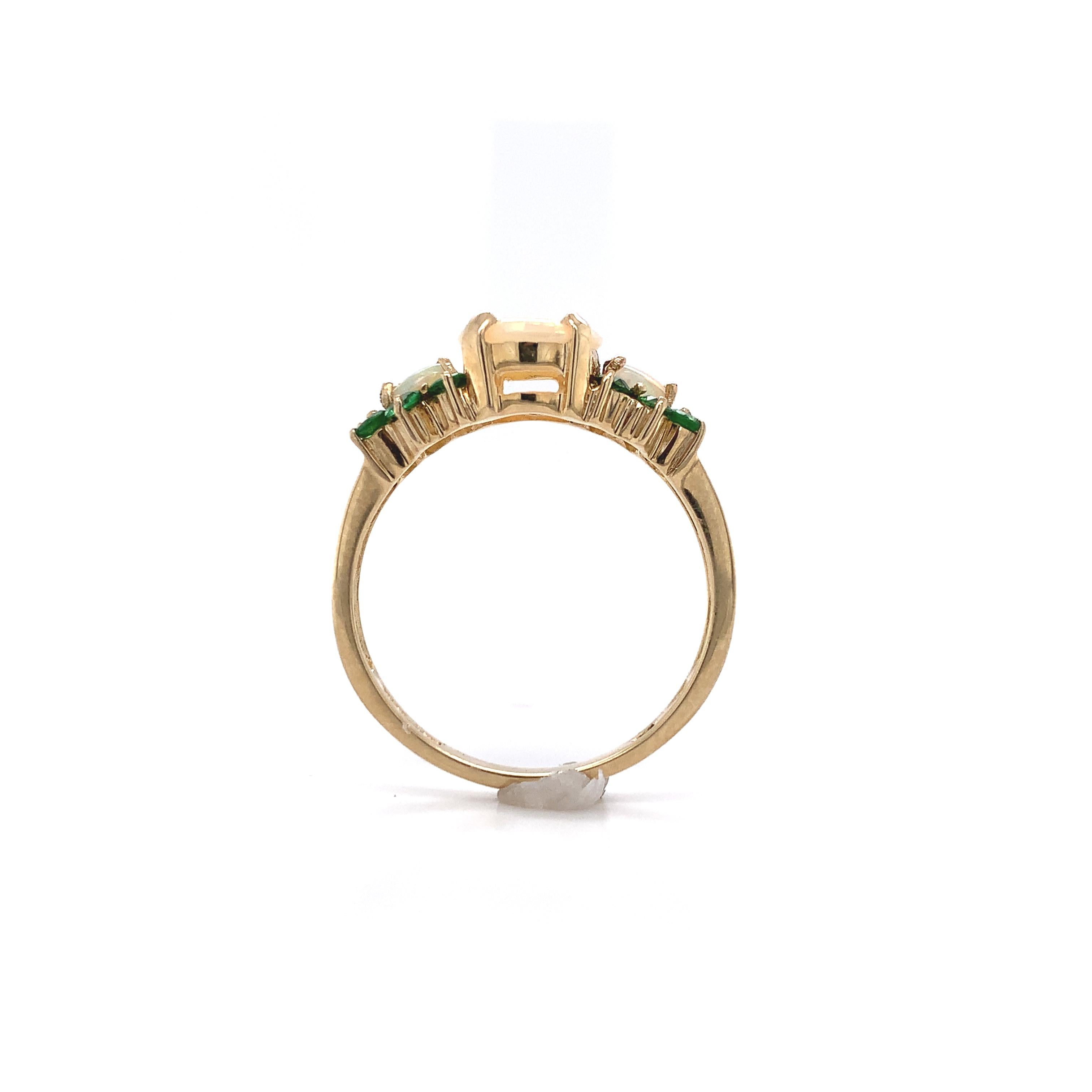 14K yellow gold ring featuring Australian opals with green garnets. The opal has lively green play of color on a white body color. The oval center opal measures about 8mm x 7.4mm and the 2 small oval opals measure about 3mm x 4mm. There are 12 small