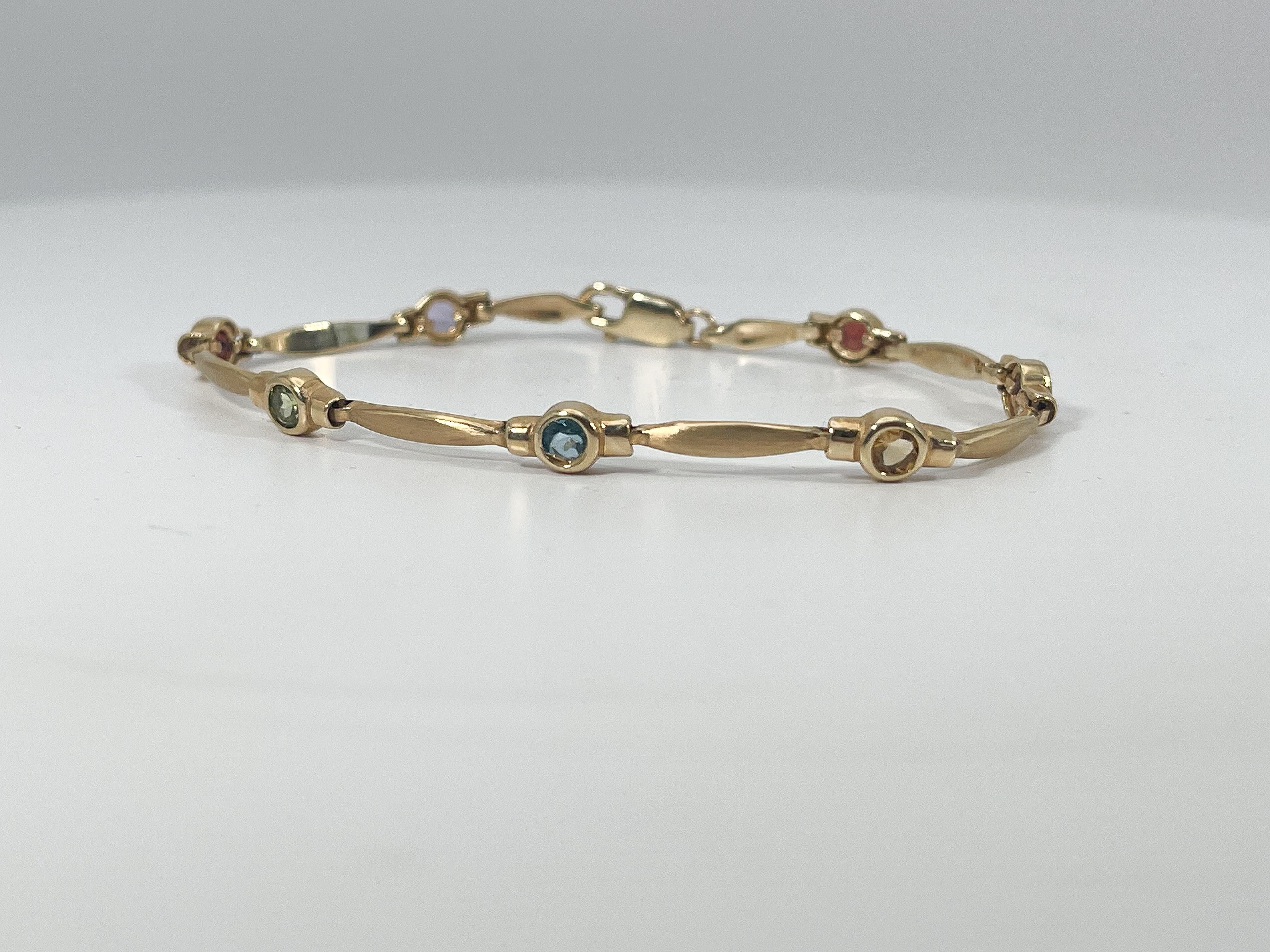 14k yellow gold round bezel set colored citrine bracelet. This bracelet has a lobster clasp, 7 stones, purple, red, green, blue, and yellow. The width of the bracelet is 5 mm, the length measures 7 inches, and has a total weight of 8.12 grams.