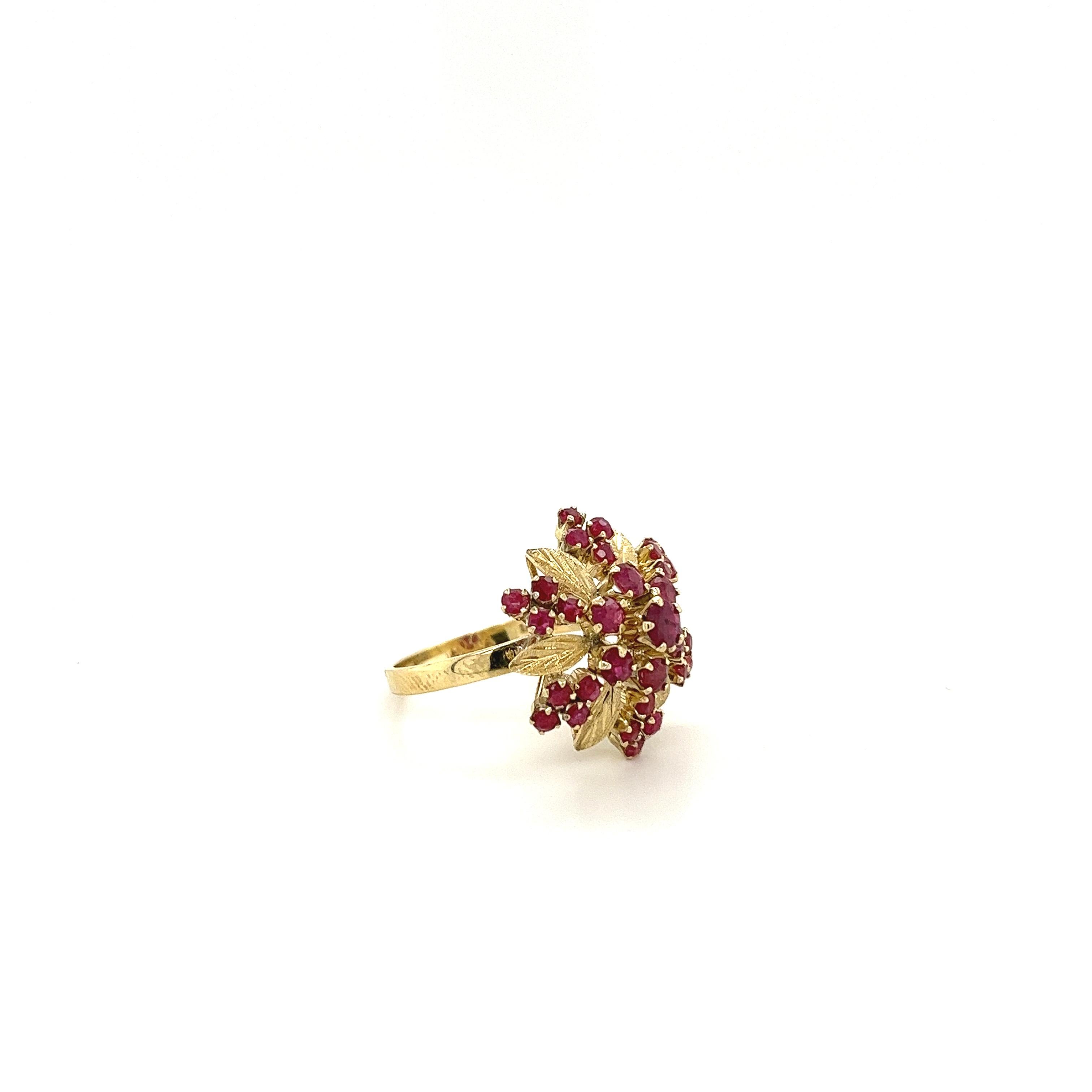 31 round-cut natural Rubies set in 5 symmetrical lines with separating carved gold flowers. A vintage Art Nouveau-inspired twist on a traditional dome cluster ring. The vibrant red Rubies create a stunning rose motif that's certain to turn heads at