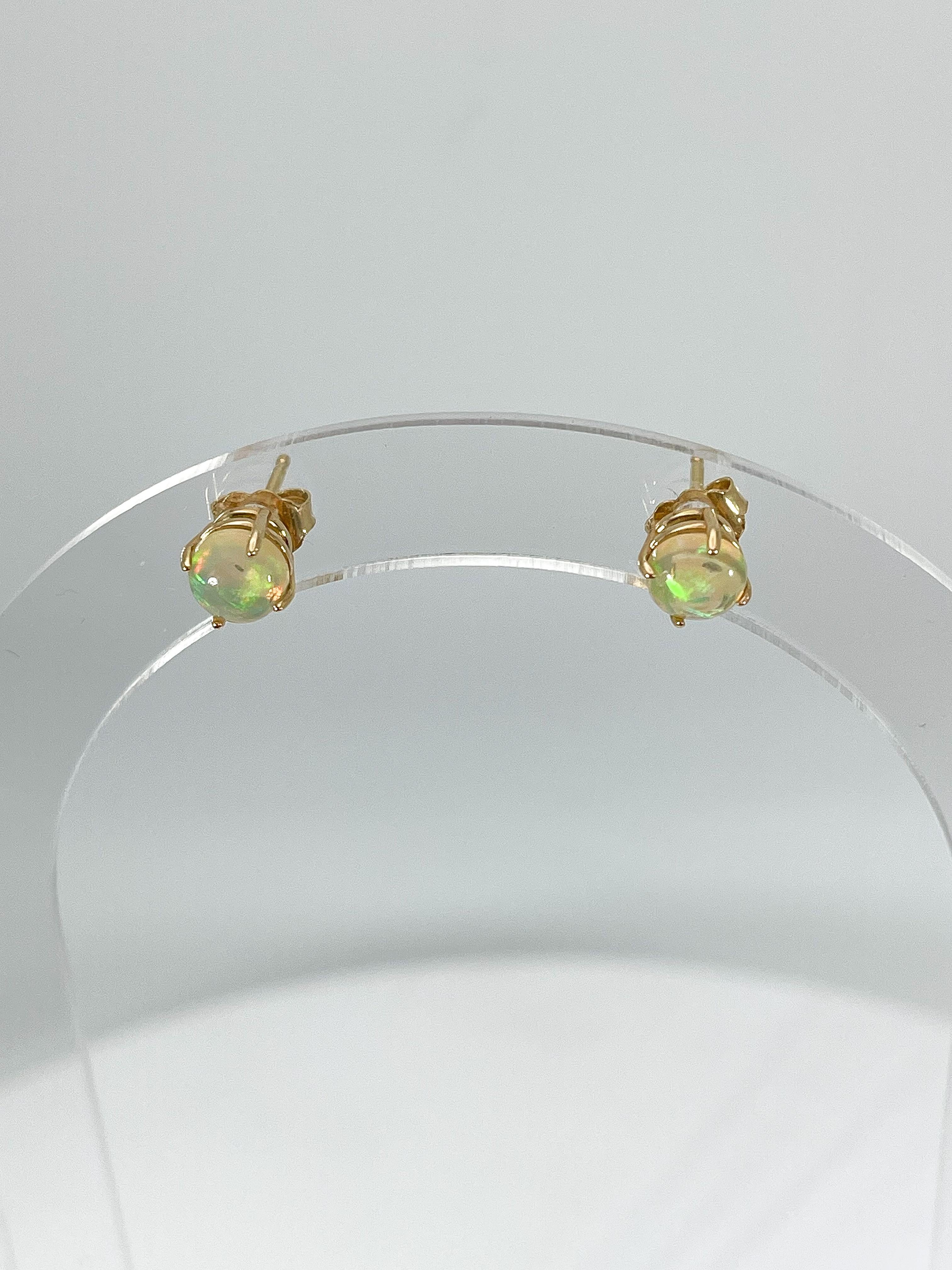 14k yellow gold round opal stud earrings. These earrings have a diameter of 6 mm, and have a total weight of 1.3 grams.