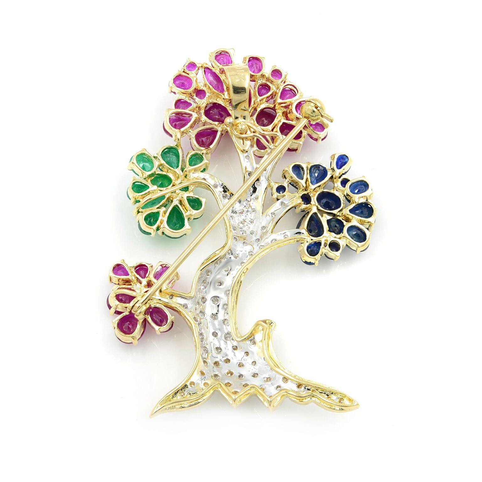 The colorful tree in this brooch, of 14 karat yellow gold, consists of vibrant ruby, emerald and sapphire petaled flowers which are accented by brilliant-cut diamonds. This style of brooch has truly endearing qualities. The jewels are described as