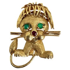 Broche lion en or jaune 14 carats, rubis et émeraudes