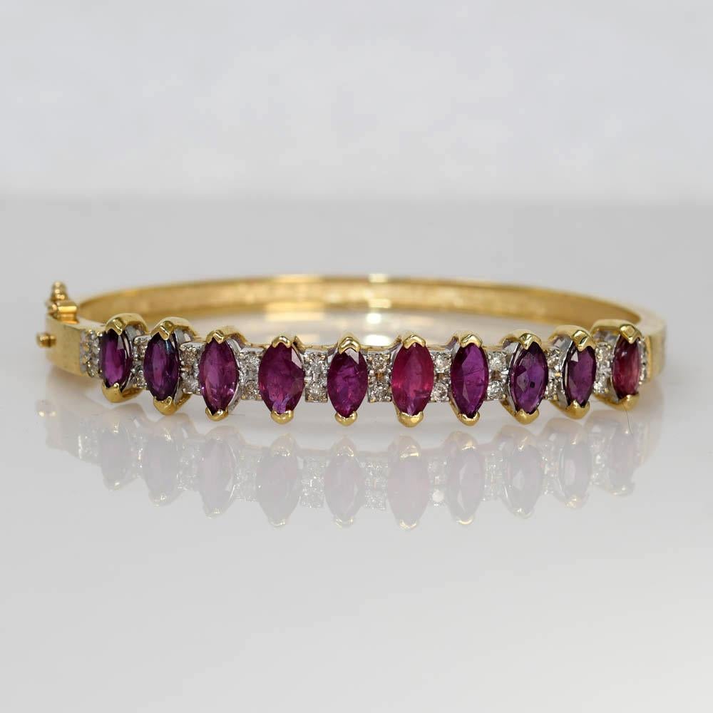 Ruby and Diamond bangle bracelet in 14k yellow gold setting.
Stamped 14k and weighs 17.8 grams.
The natural rubies are marquise shaped, 3.00 total carats, purplish-red colors.
The diamonds are round brilliant cuts. .50 total carats, K color, Si to