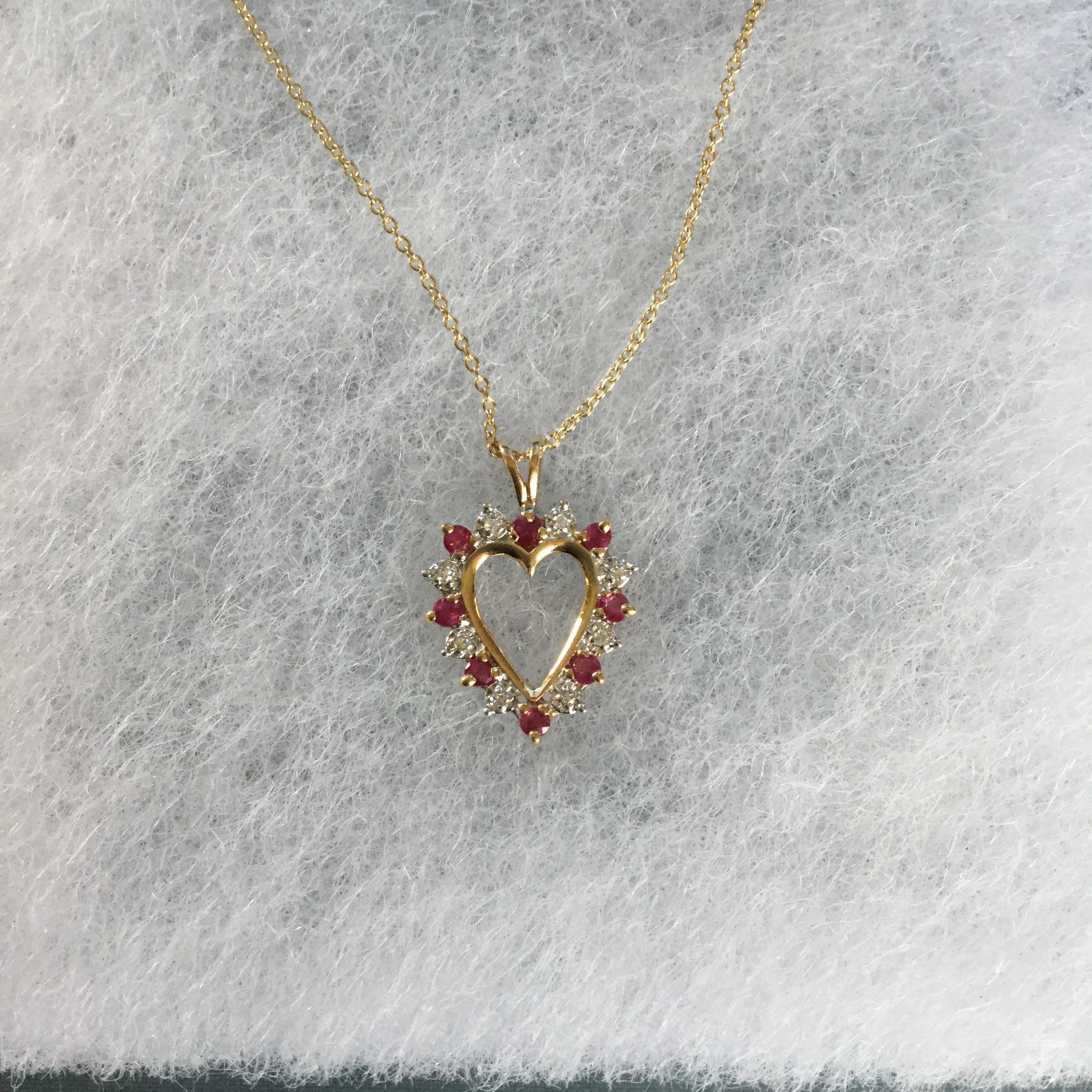 14K Yellow gold ruby and diamond heart shaped pendant necklace. The rubies weigh approx. 0.50 ctw and the diamonds weigh approx. 0.50 ctw. The pendant hangs on a 16 inch cable chain.  