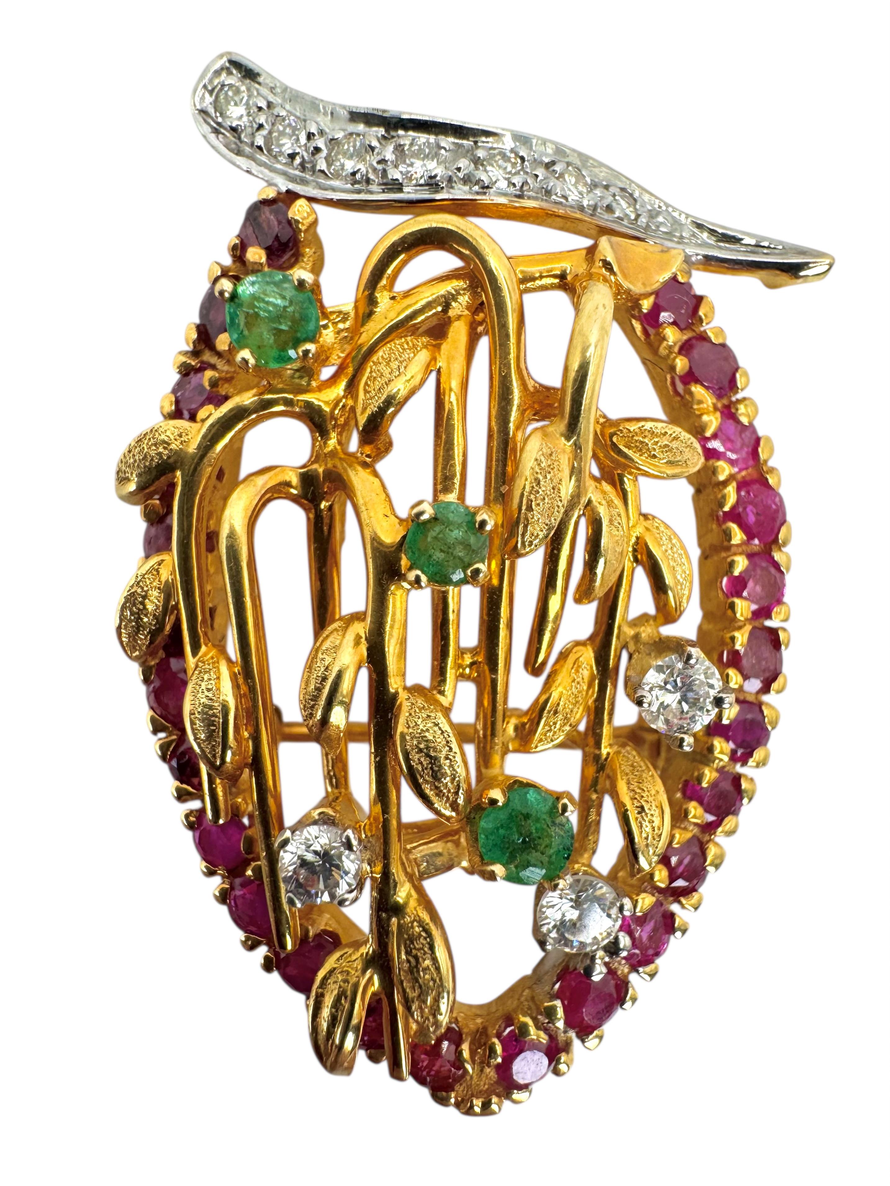 Cette broche vibrante en forme de feuille est réalisée en or jaune 14 carats et est entourée de 25 rubis de taille ronde totalisant 1,50 carat. Les accents comprennent 10 diamants ronds totalisant 0,37 carat et 3 émeraudes vives de 0,27 carat,