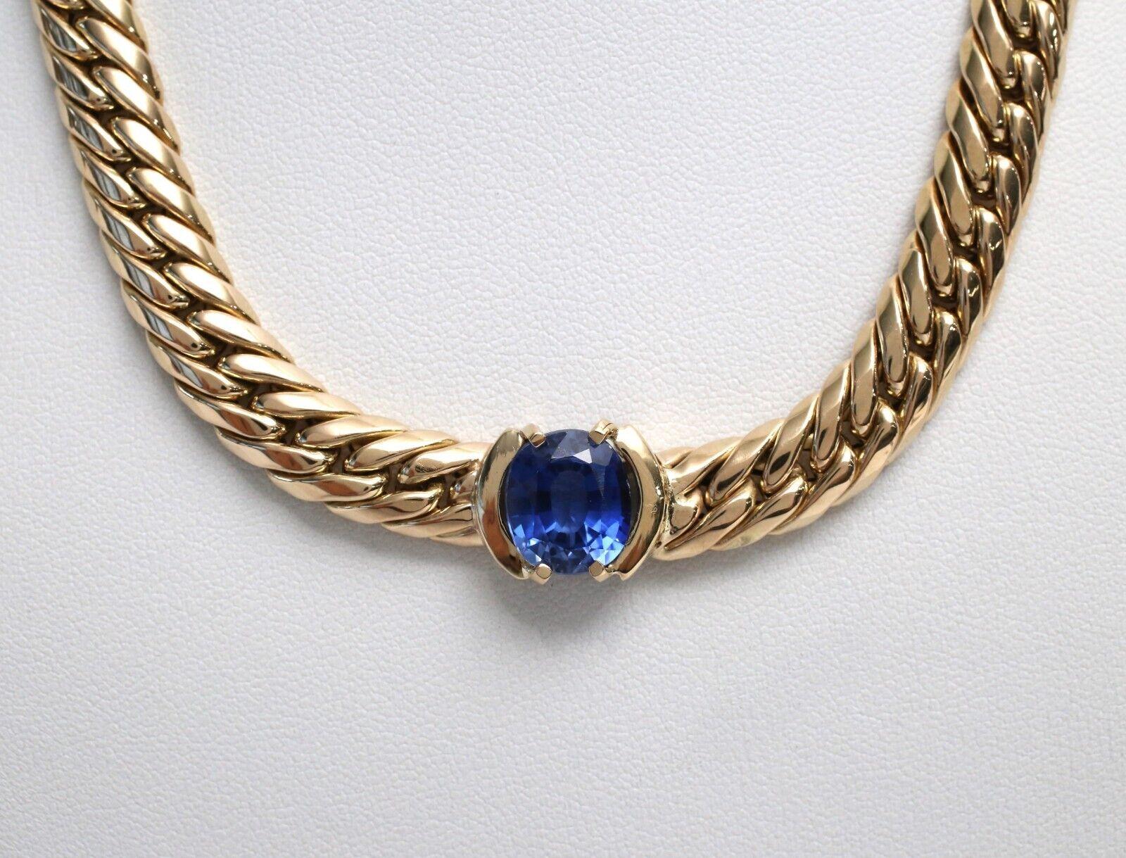 This exquisite 14k yellow gold shaker choker necklace is a timeless piece that exudes elegance and sophistication. The necklace features a luxurious gold link design, creating a bold yet refined aesthetic. At its center, a striking oval-cut blue