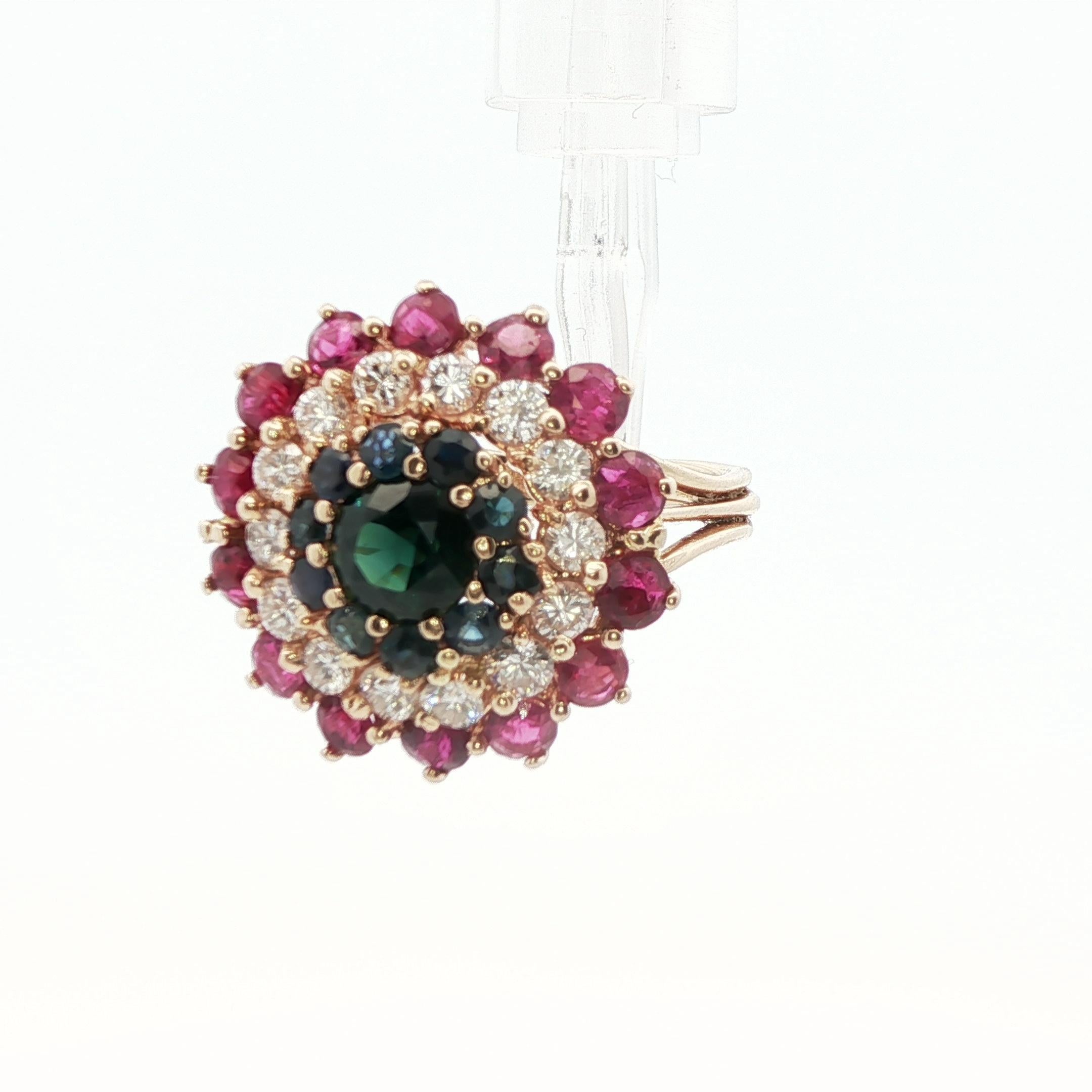 This beautiful cluster ring is made in 14k yellow gold with an exceptional combination of natural sapphire, ruby and diamond. The center of the ring showcases a 1 carat rich blue sapphire with a halo of gemstones surrounding it. The first layer of