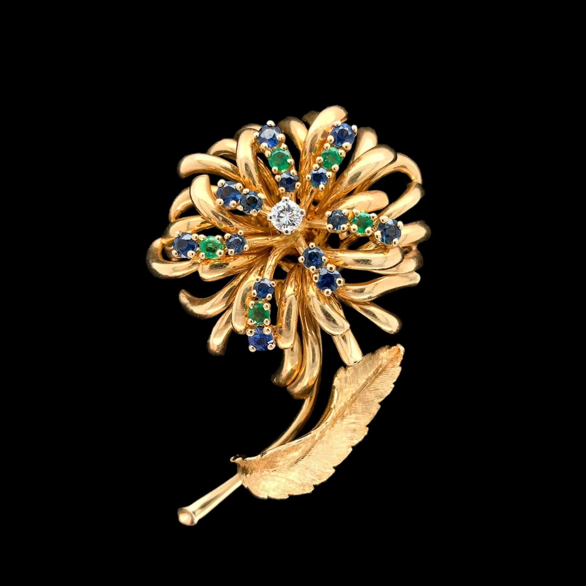 14K yellow gold diamond, sapphire, and emerald pin made by Dan Frere. The round brilliant cut diamond measures about 3.5mm. There are 14 round blue sapphires measuring about 2.5mm - 2.7mm. There are 5 round emeralds measuring about 2.5mm. The pin