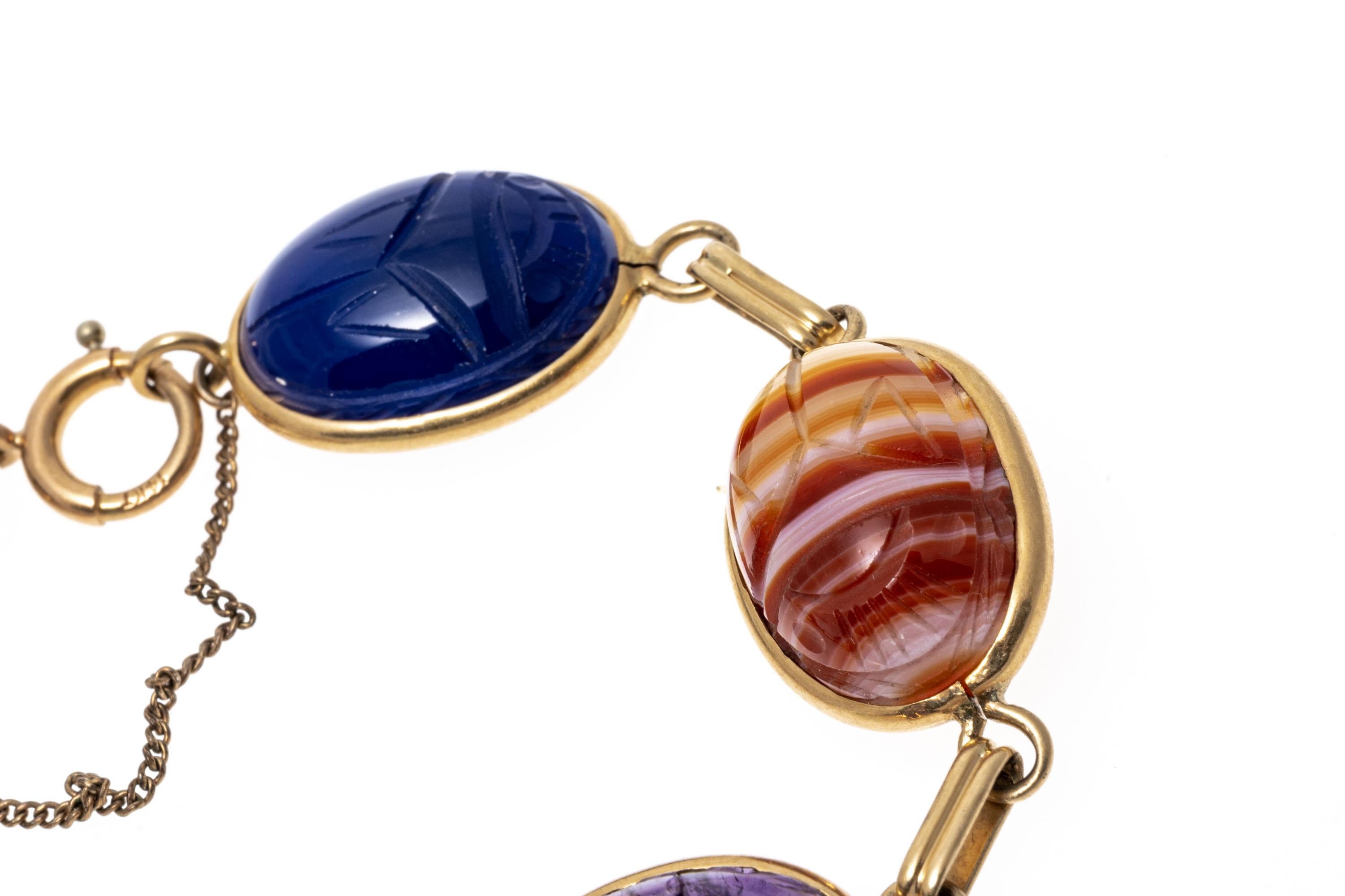 14k Yellow Gold Scarab Link Bracelet
This attractive bracelet is a scarab link style, set with carved tigers eye, rhodonite, green chalcedony, amethyst, agate and blue onyx stones, bezel set. The bracelet has a spring ring style clasp with a safety