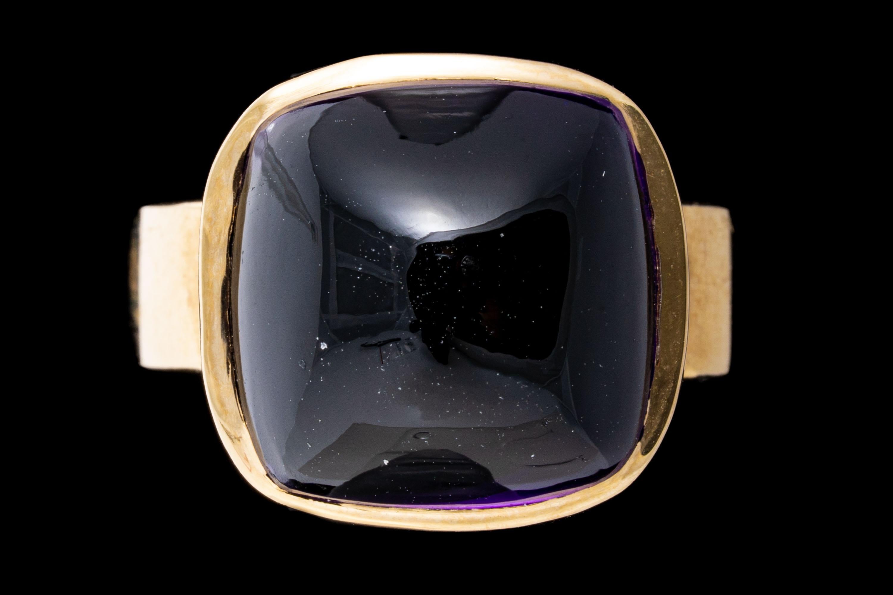 14k yellow gold ring. This lovely ring has a square sugarloaf cabochon cut dark purple color amethyst center, bezel set atop a modern profile, and wide, high polished yellow gold band.
Marks: 14k
Dimensions: 9/16