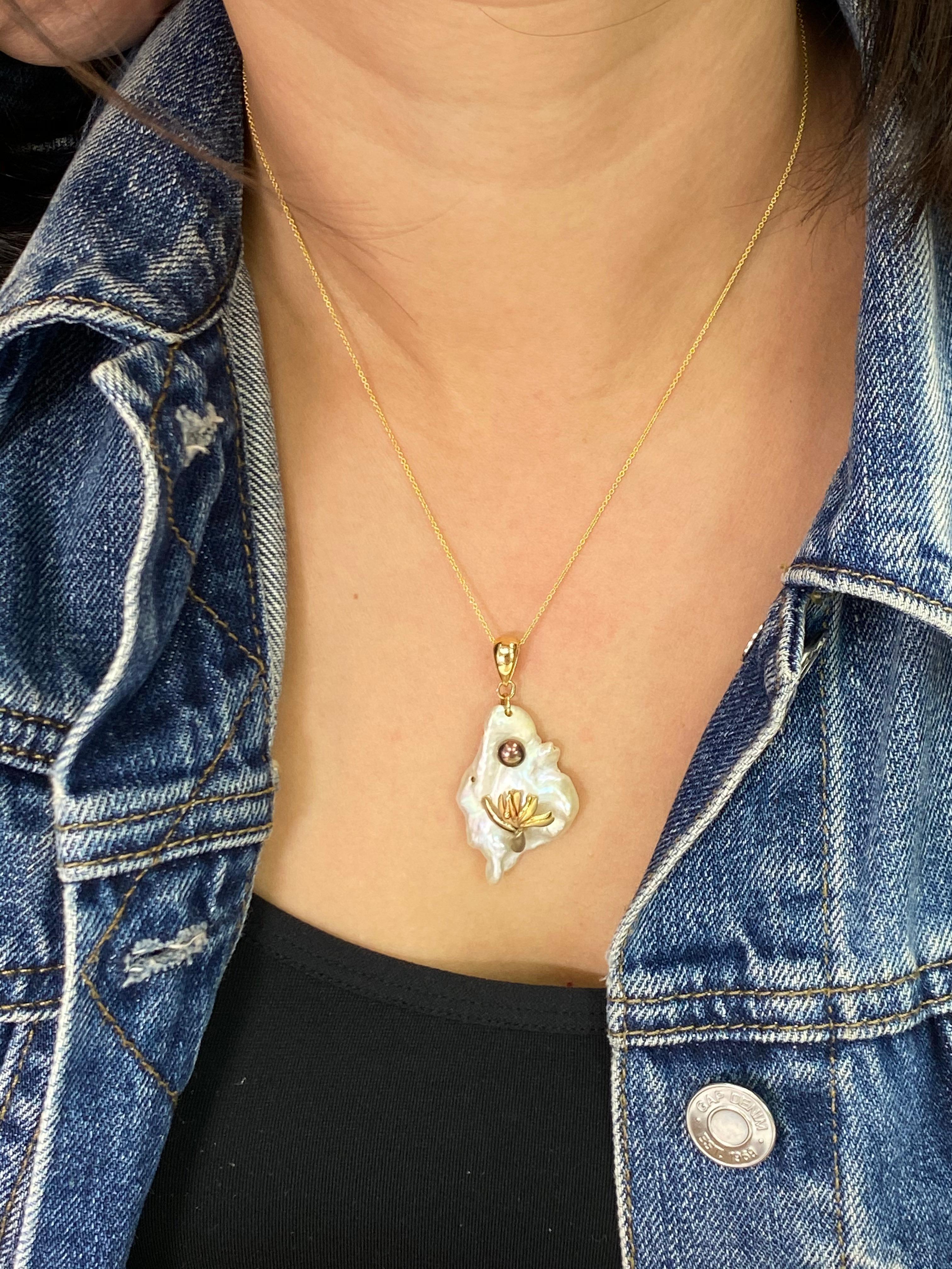 This is a super unique one of a kind pendant. This mother of pearl has a natural irregular shape with excellent luster. The pendant is set in 14k yellow gold. There is a round color changing Tahitian black pearl along with 14k yellow gold 