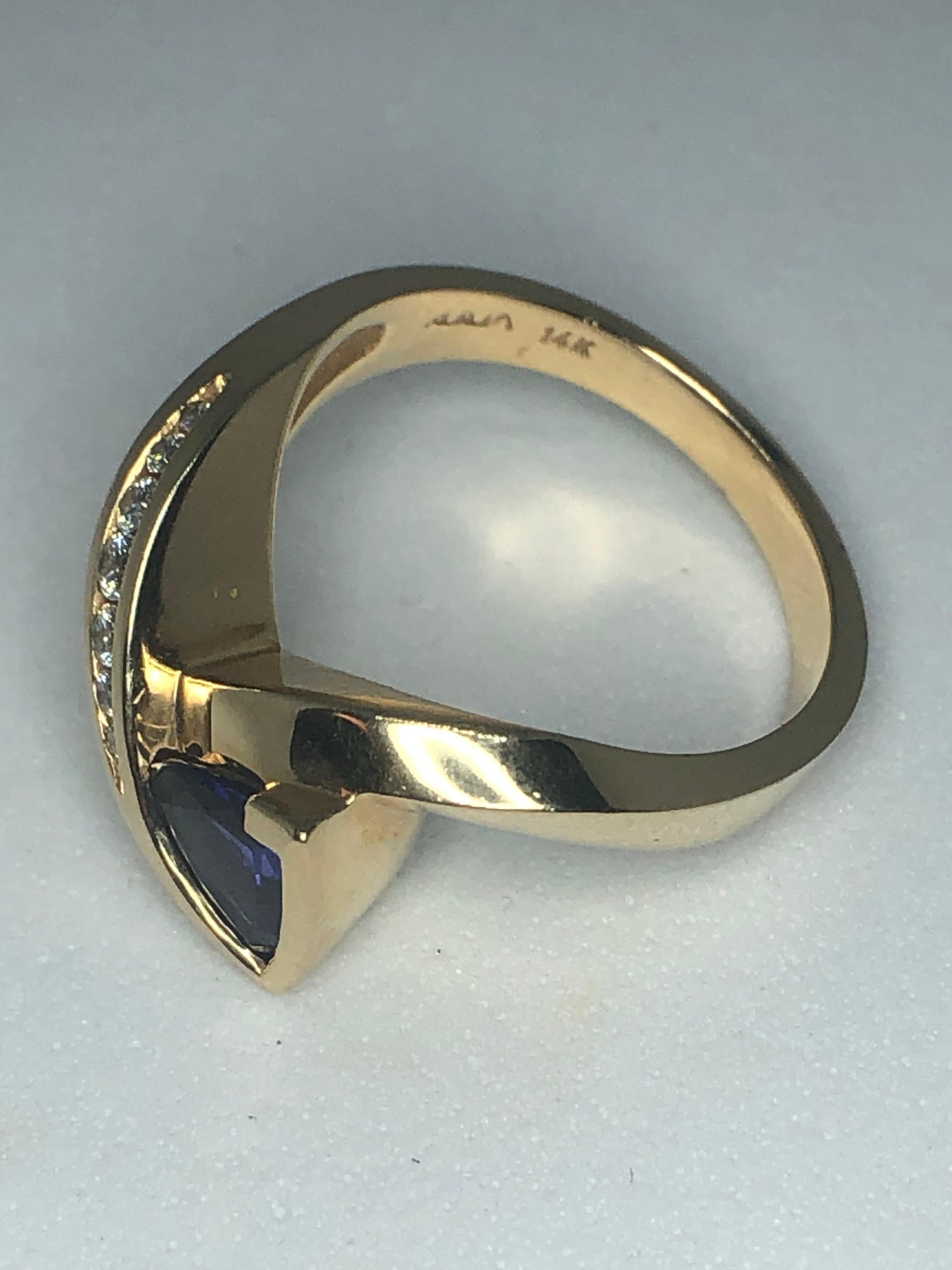 Lady's 14kt yellow gold tanzanite and diamond ring by Aurum, style # A-270, 1 - 6mm trillion shaped tanzanite = .75ct, medium purplish blue, full cut round diamonds = .14ct, average color G-H, average clarity VS2-SI1, 4.1dwt. Size 6