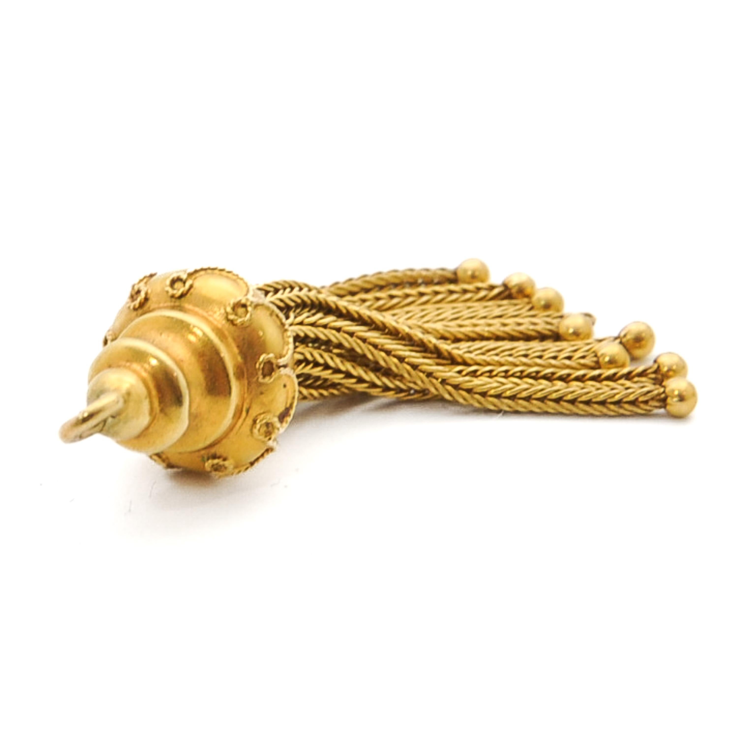 A Victorian foxtail tassel pendant crafted in 14 karat yellow gold. This pendant is beautifully detailed with a rope decor on top of the cap above the dangling tassels. The lovely tassels consist of foxtail woven chains, while the caps below keeps