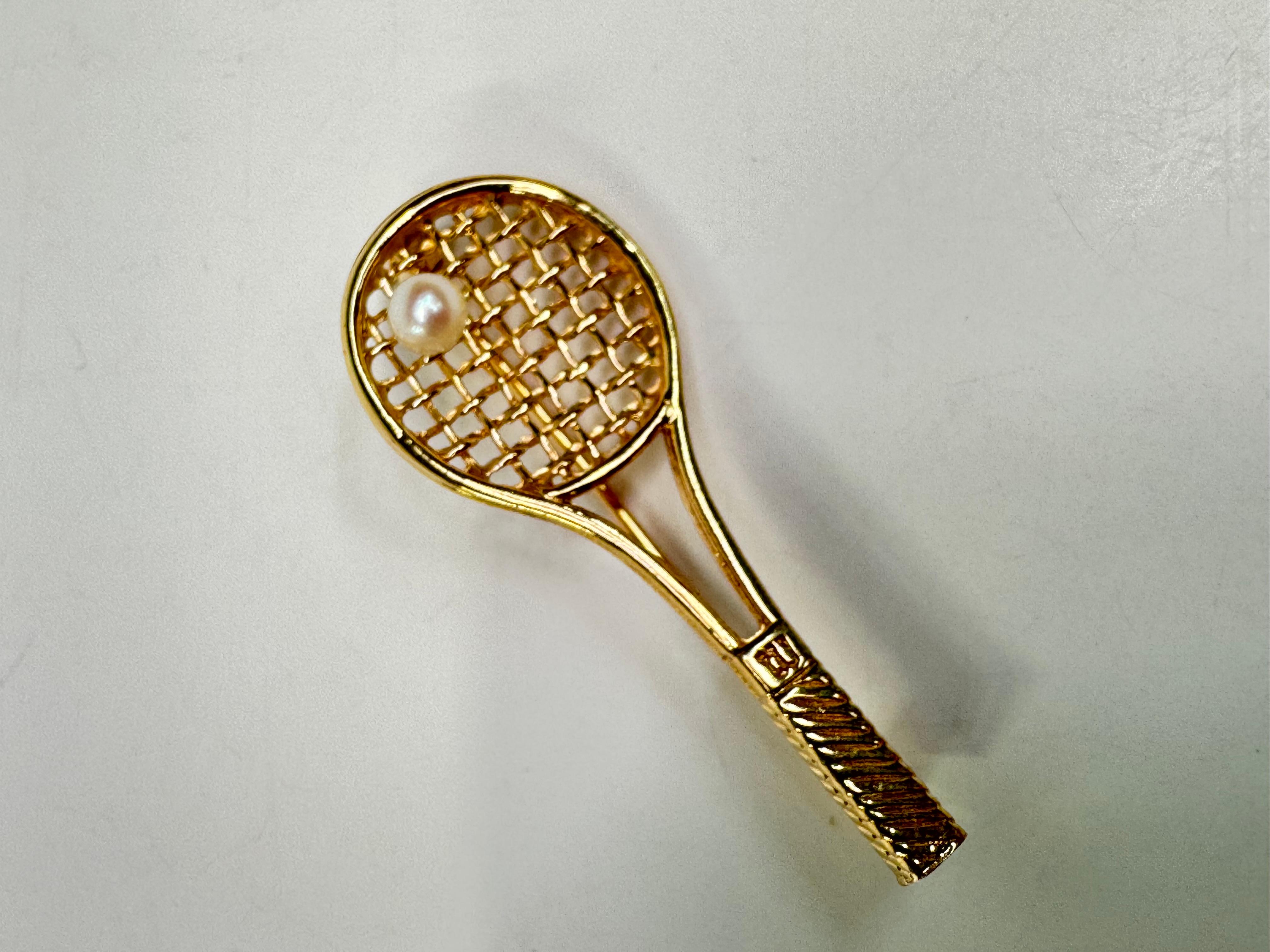 Cette broche unique en or jaune 14 carats en forme de raquette de tennis est un modèle classique avec une touche de raffinement. Réalisée avec soin en or jaune 14 carats, cette élégante pièce présente une raquette de tennis magnifiquement détaillée,