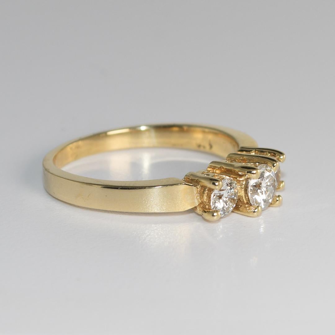 This 14-karat yellow gold ring weighs 3.60 grams.
It contains three round brilliant diamonds, with a total carat weight of 0.69.
The diamonds are mounted in a prong setting and have a clarity of SI2-I1.
This ring is a size 8, and it is in its finest