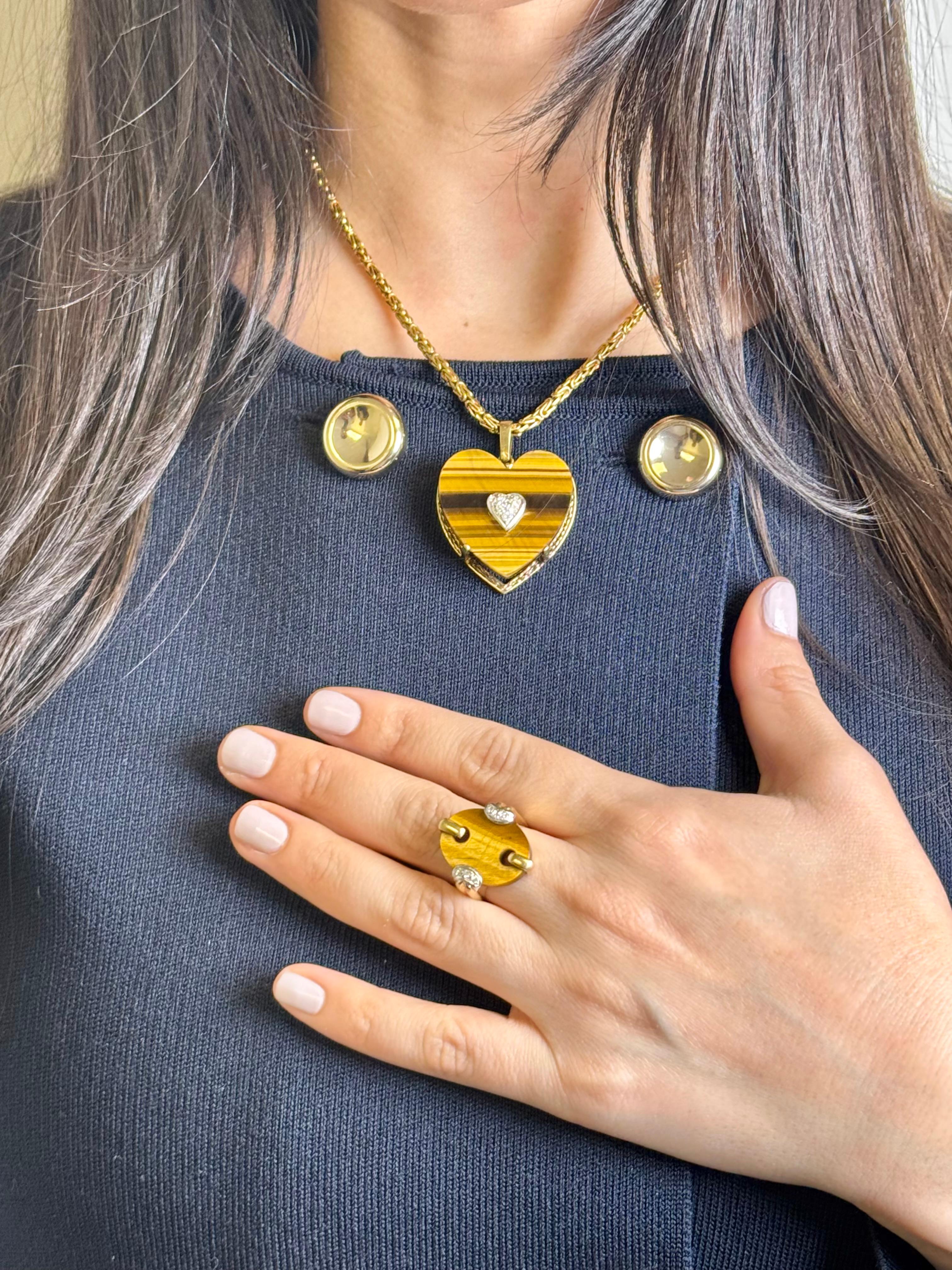 Audacieux et romantique à la fois, ce collier vintage présente un pendentif œil de tigre en forme de cœur magnifiquement sculpté, serti dans un riche or jaune 14 carats. En son centre se trouve un motif de cœur en diamant serti en pavé totalisant