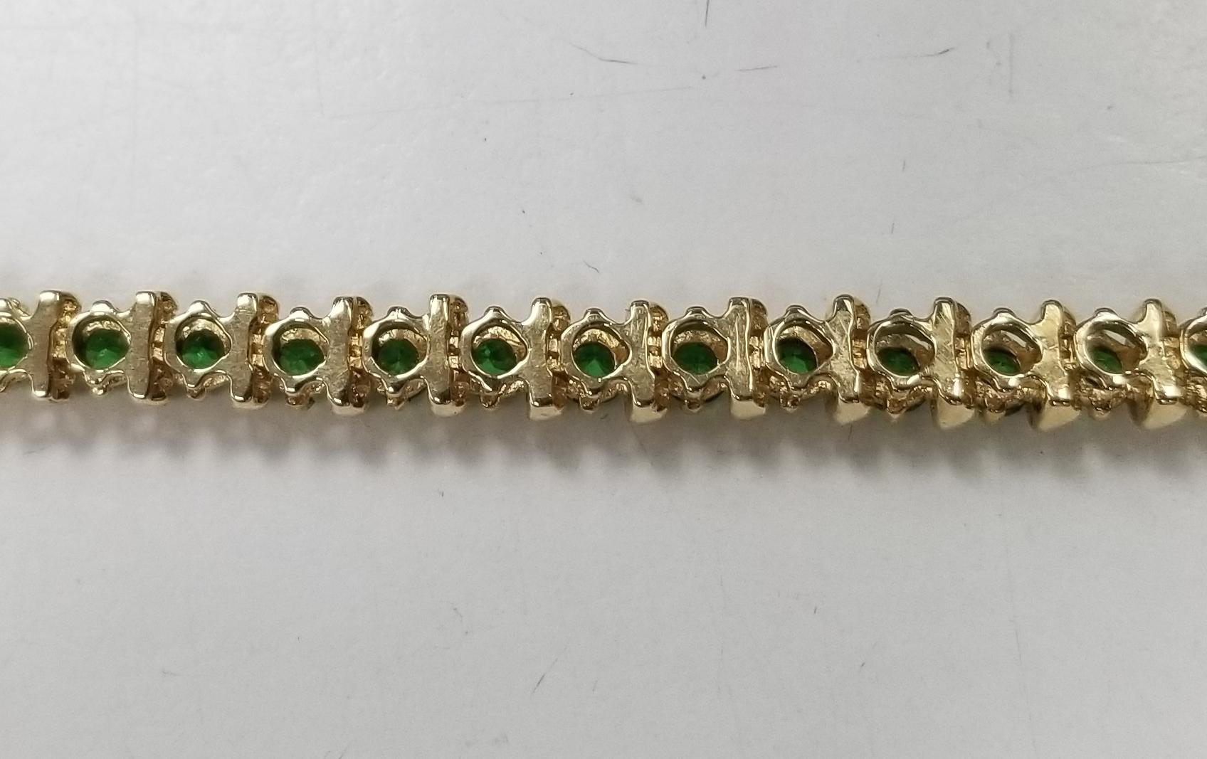 14k yellow gold tsavorite and bar bracelet, containing 40 round cut tsavorite of gem quality weighing 5.00cts. measuring 7 inches with clasp and safety. 