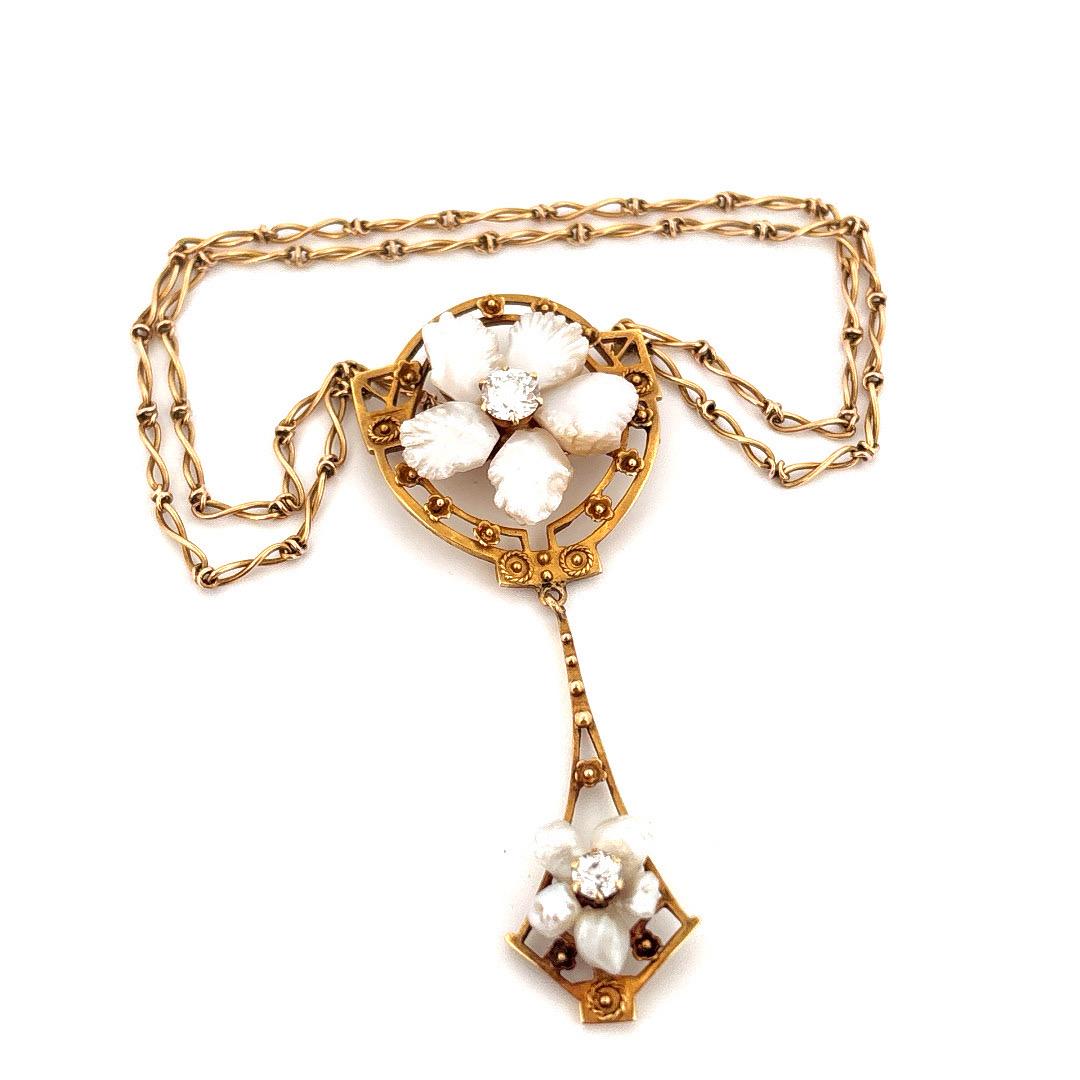 Diese exquisite Halskette aus 14-karätigem Gelbgold strahlt den Charme des Jugendstils aus und ist eine seltene Mischung aus Kunstfertigkeit und Eleganz. Das Schmuckstück zeigt kunstvoll von Hand geschnitzte weiße Muschelblumen, in deren Mitte
