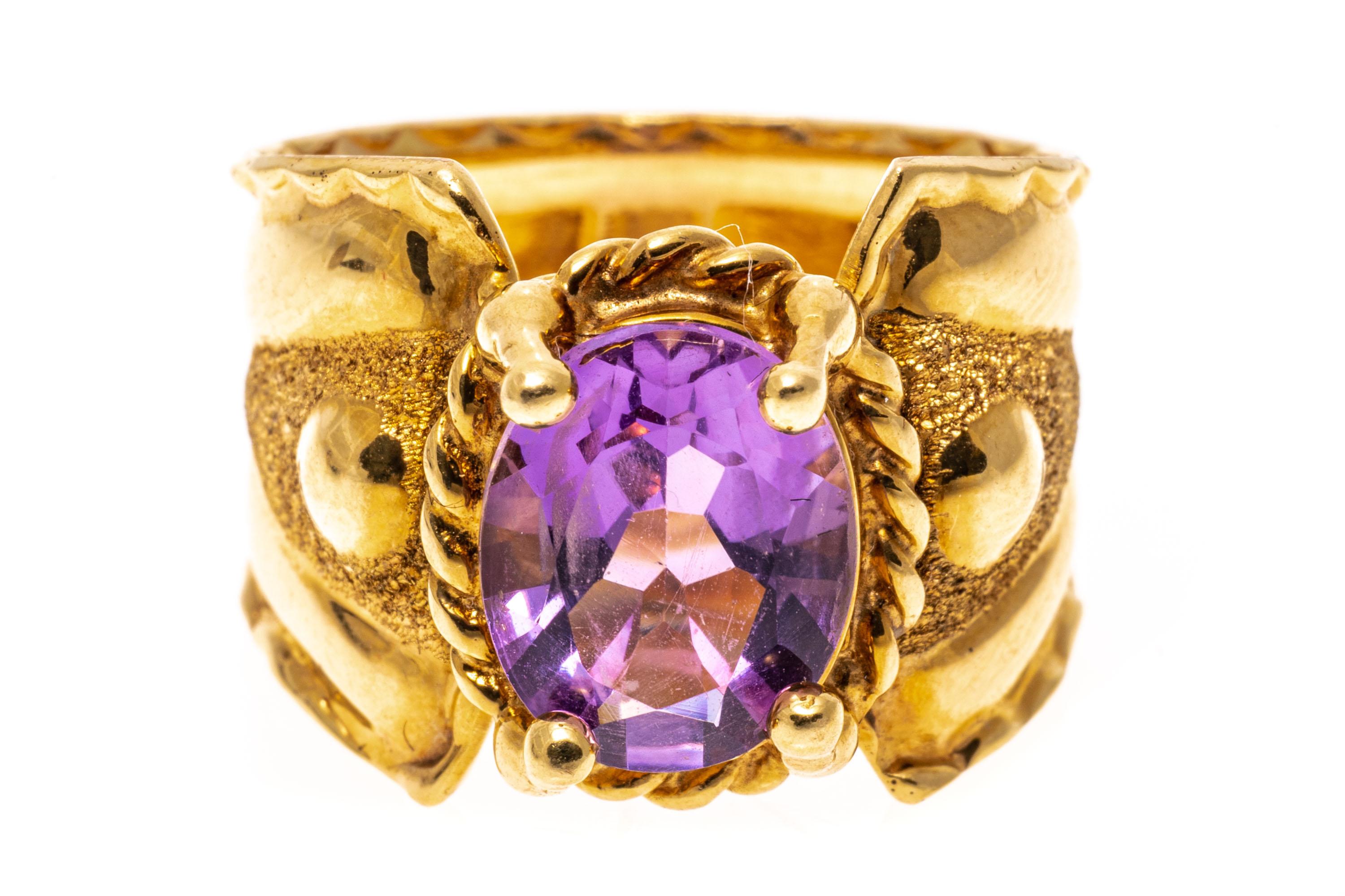 14k yellow gold ring. This striking ring is an ultra wide, tapered band, set with a center oval faceted, light purple color amethyst, approximately 2.06 CTS, prong set and trimmed with a rope edged border. The ring is finished by a sandblast