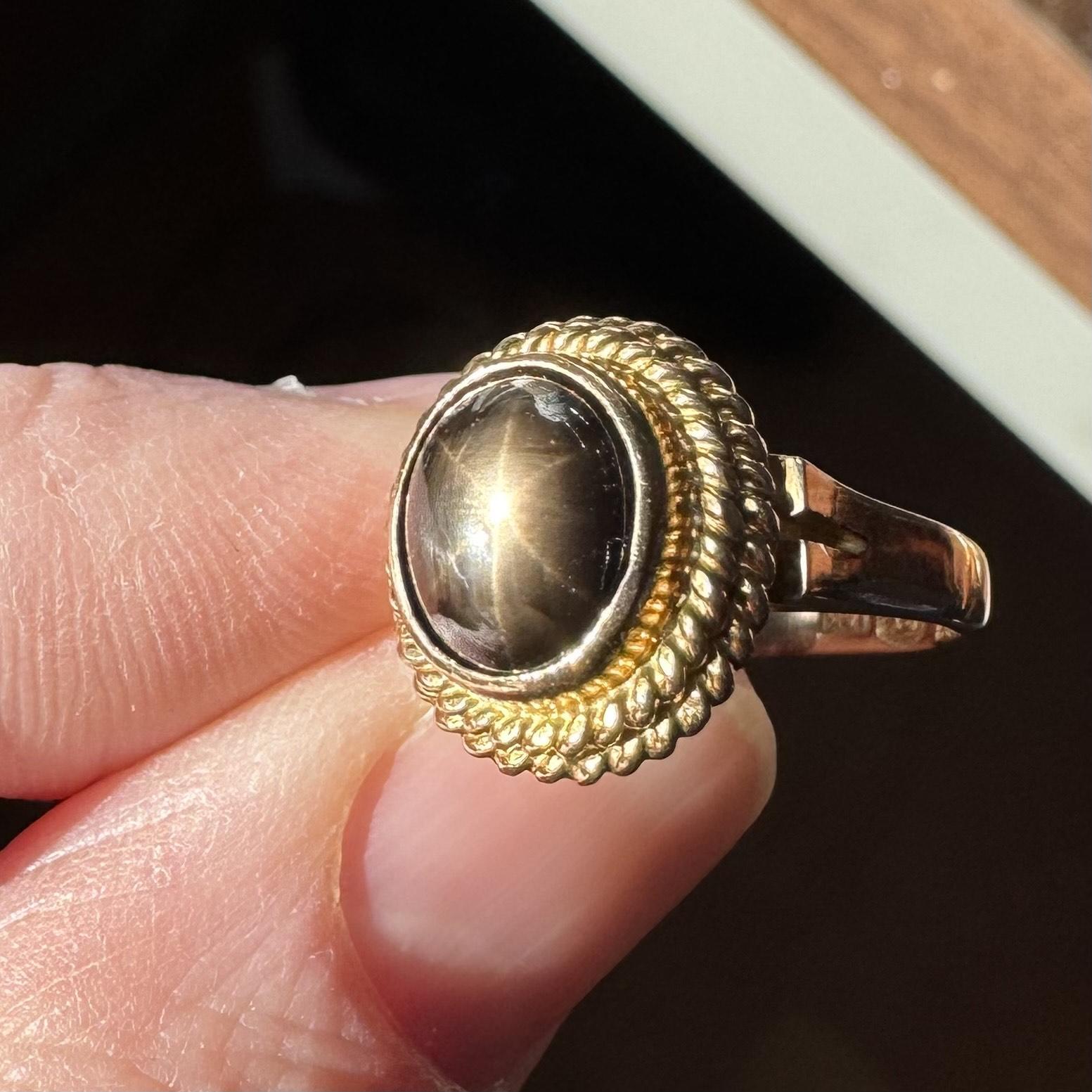 Condition:  Excellent Condition, Professionally Cleaned and Polished
Metal:  14k Gold (Marked, and Professionally Tested)
Weight:  6.9g
Gemstone:  Oval Cabochon Brown Star Sapphire
Band Width:  2.5mm
Size:  4.5
Markings:  