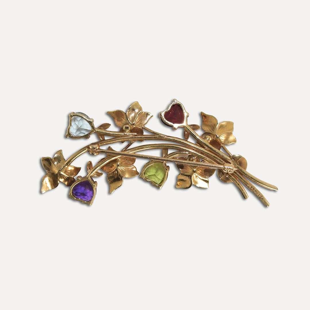 Vintage floral design gemstone brooch.
Stamped 14k and weighs 6.3 grams.
There are four heart-shaped gemstones, garnet, peridot, amethyst, and aquamarine.
The brooch measures 2 inches long and 3/4 inches wide.
Excellent condition.