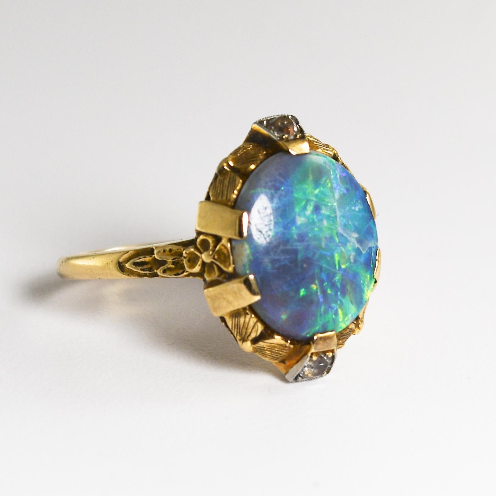 Vintage opal and diamond ring in 14k yellow gold floral design mounting.
Stamped 14k, Plat, and weighs 3.5 grams gross weight.
The Australian black opal has excellent, bright green and blue colors.
The opal is a solid piece measuring 11.5mm by