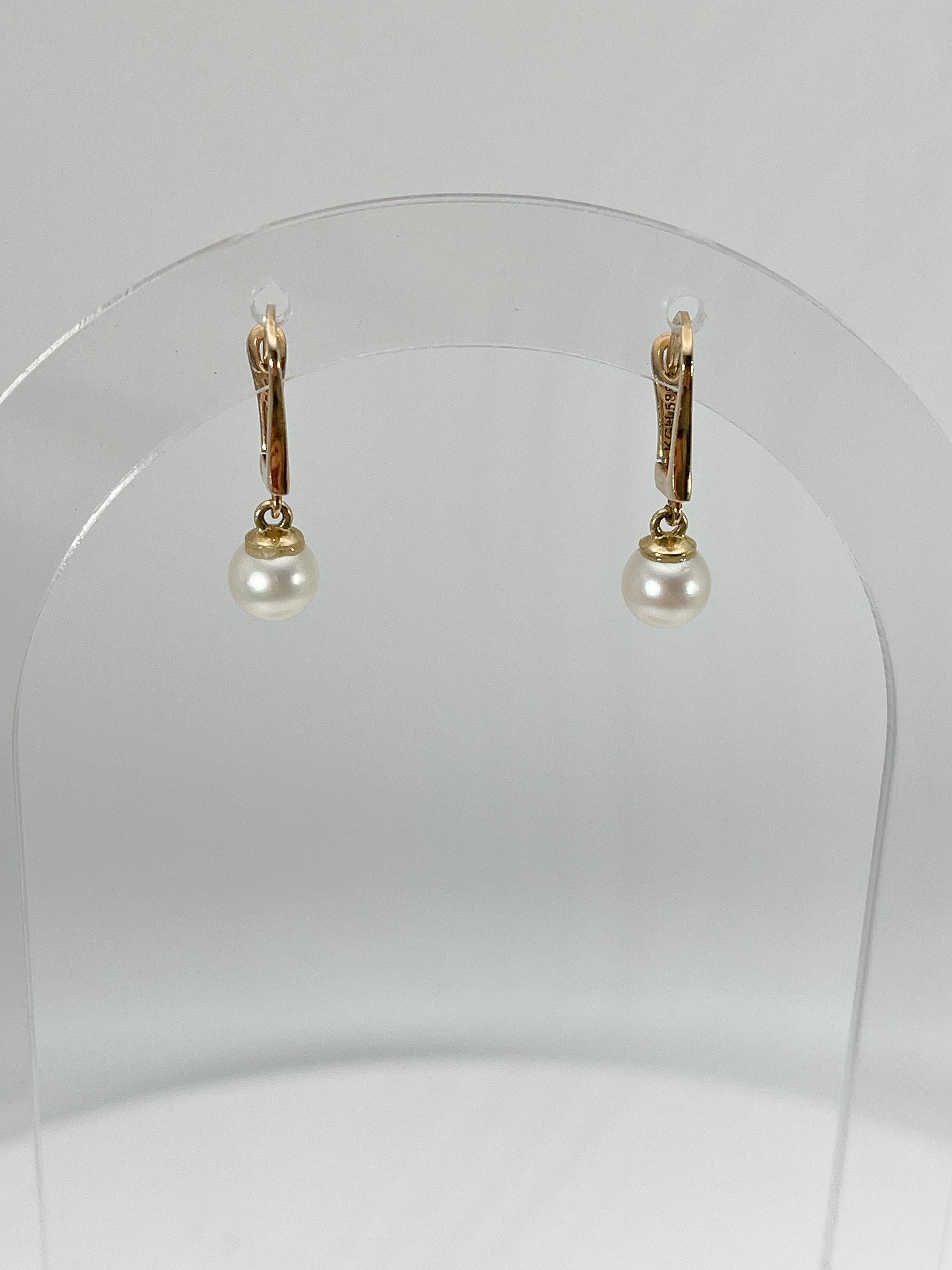 Boucles d'oreilles pendantes en or jaune 14k et perles blanches. La longueur de ces boucles d'oreilles est de 20,5, le diamètre de la perle est de 6 mm et leur poids total est de 2,06 grammes.