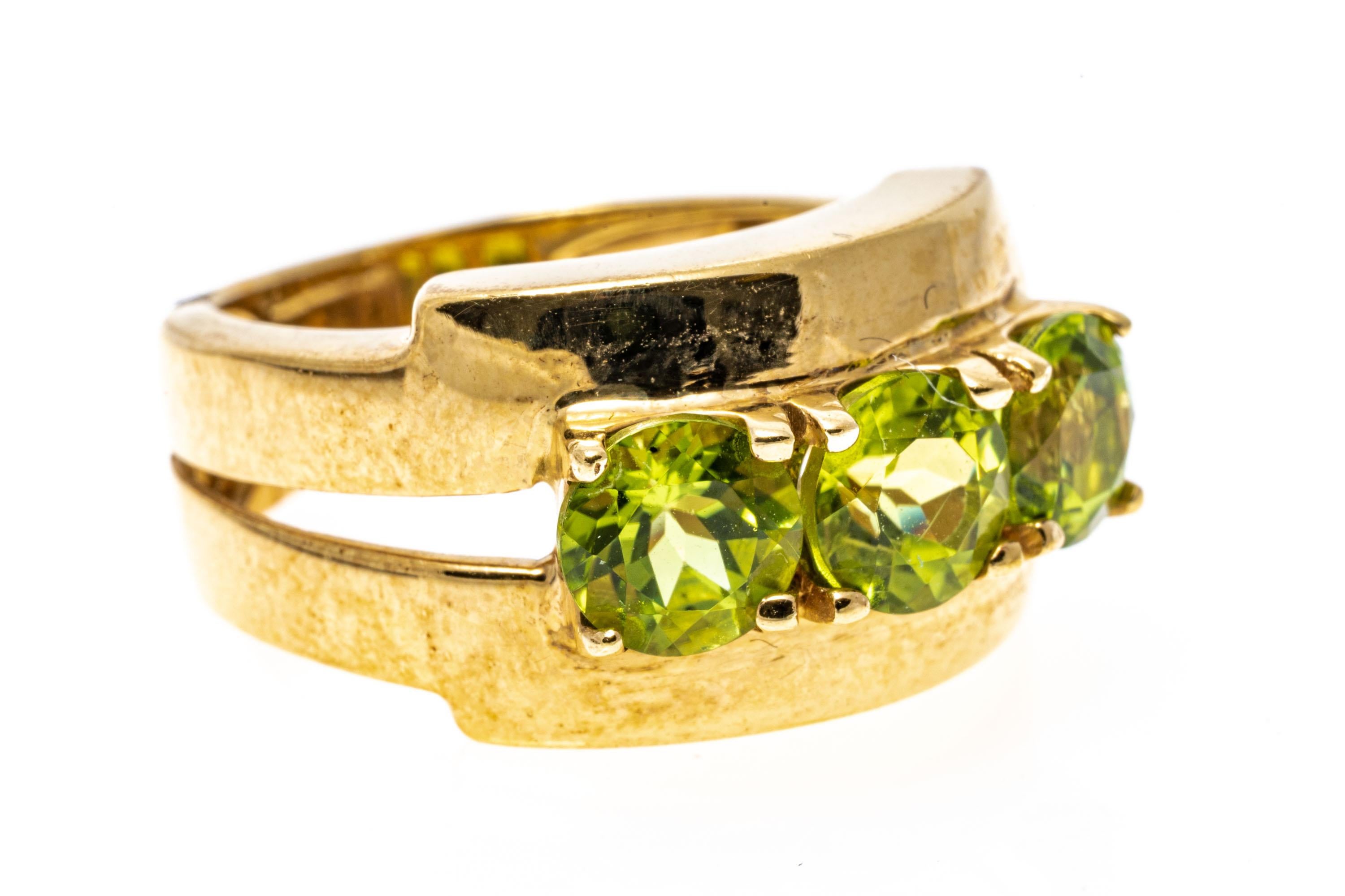 14k yellow gold ring. This yellow gold, wide contemporary split ring, set across the top with three round faceted, chartreuse green color peridots, approximately 2.40 TCW, prong set.
Marks: 14k
Dimensions: 5/8