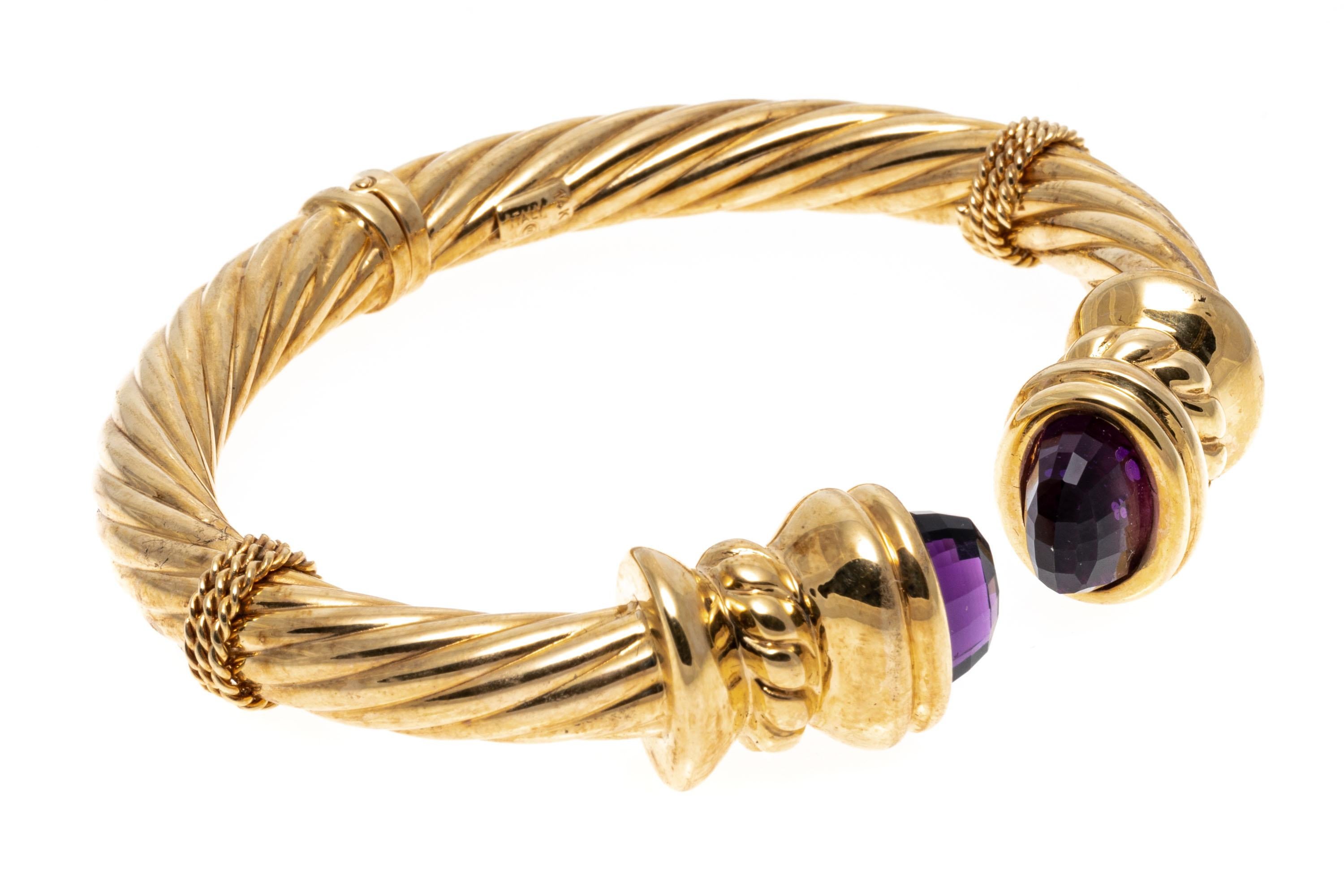 armband aus 14k Gelbgold. Dieses auffällige Armband mit Scharnier ist ein breites, geripptes Modell, das mit einem Seilmuster verziert ist, das in geraffte Enden mündet, die mit dunkelvioletten, facettierten Amethysten besetzt sind.
Markierungen: