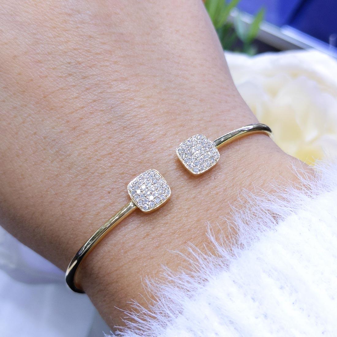Dieses elegante Drahtarmband aus 14-karätigem Gold strahlt Raffinesse und Luxus aus. Das schlanke, minimalistische Design wird durch zwei atemberaubende, mit Diamanten besetzte quadratische Enden mit insgesamt 0,38 Karat Brillanten veredelt. Das