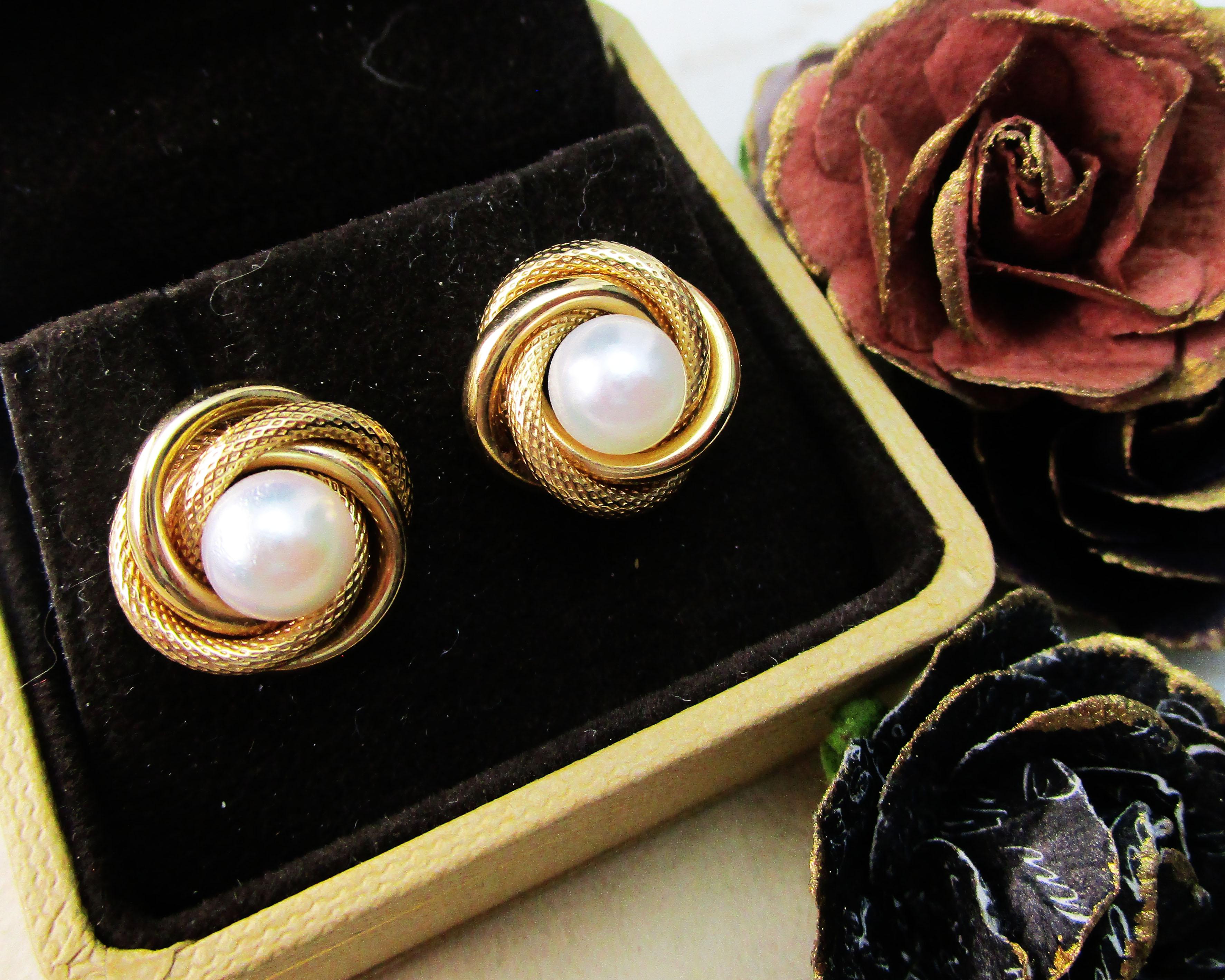 This is a gorgeous pair of stud earrings in 14k yellow gold featuring brilliant white pearl earrings and a braided love knot border of textured and smooth 14k gold! These are not your everyday pearl studs! They have the classic pearl center, but the