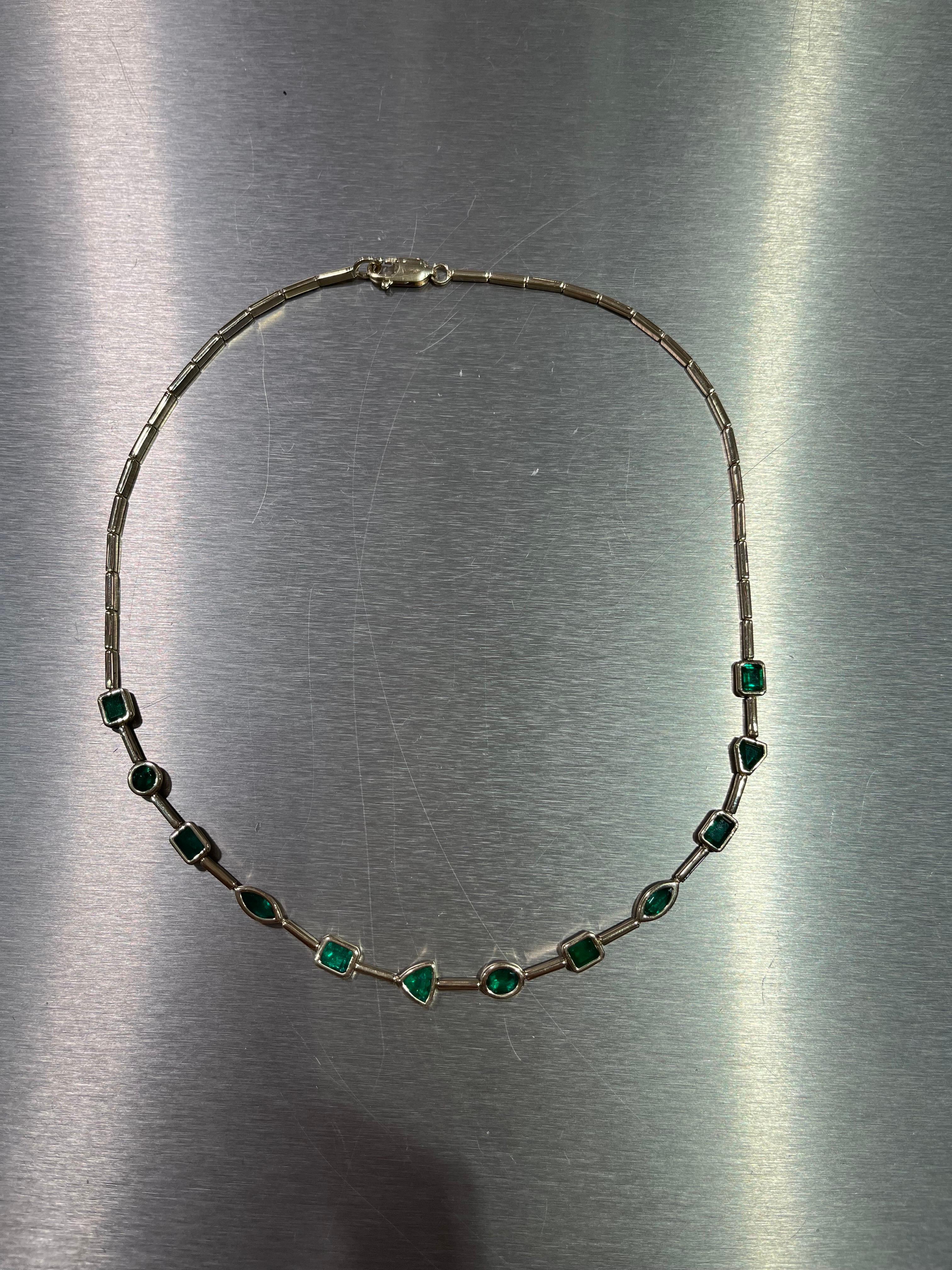 Fancy shape green emeralds set in 14K yellow gold. The necklace is set with 12 different shape stones ranging from 0.45-0.50 carats each. The necklace is set with mixed emerald, ovals, rounds, marquise, and triangle shaped stones. The total weight