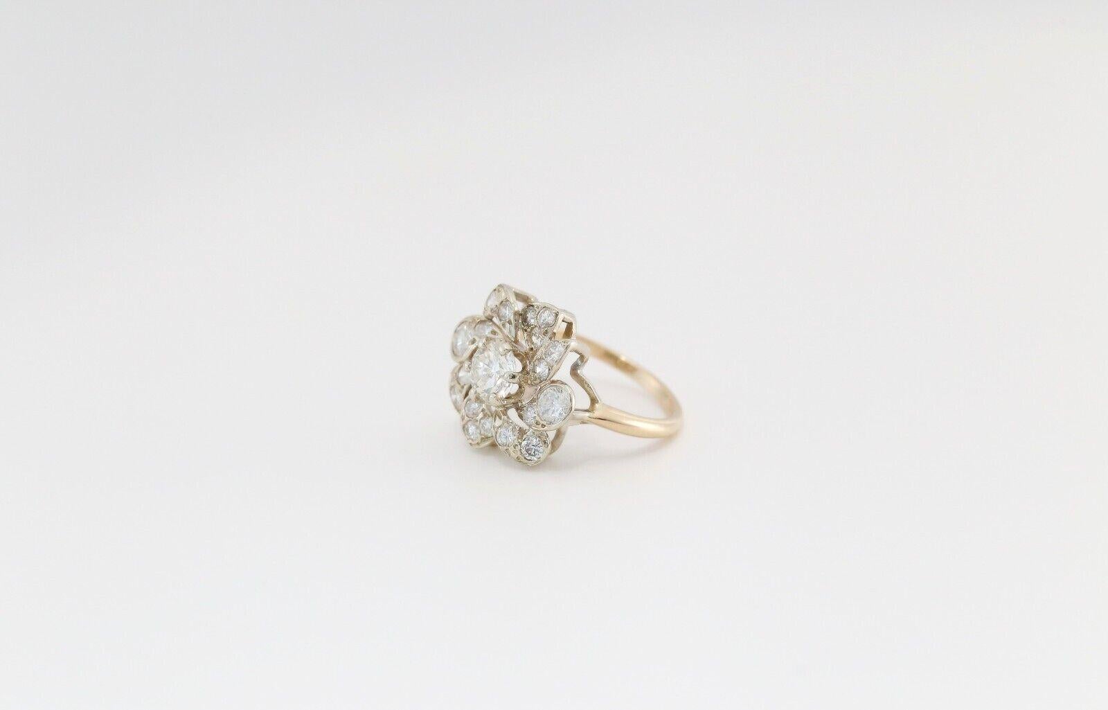 This dazzling 14k yellow & white gold ring showcases a stunning floral-inspired design, centered around a brilliant round-cut diamond. Surrounding the center stone are elegantly arranged pear and round-shaped diamonds, forming a dynamic,