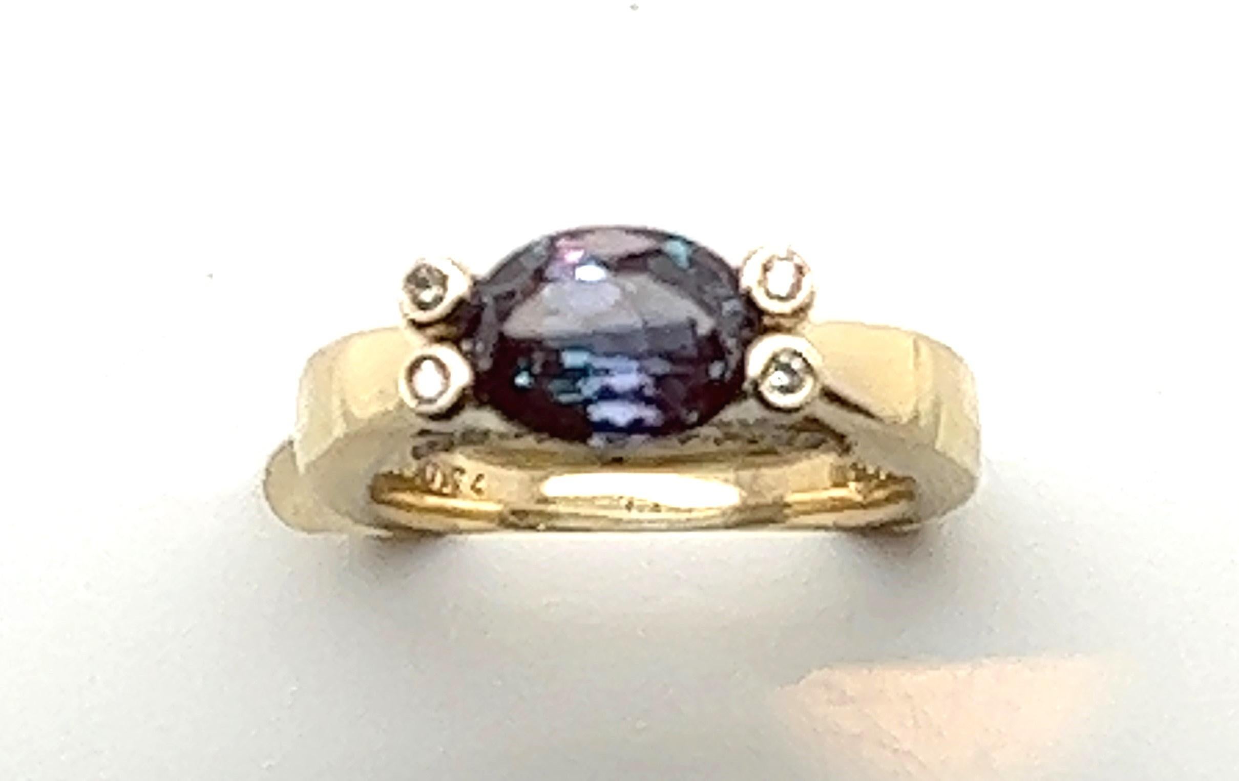 14kt yellow gold ring with a center oval 2.52 carat synthetic alexandrite ring set horizontally (east-west). There are four bezel set diamonds at the top of each prong and diamonds set in the side of the setting so there's something beautiful no