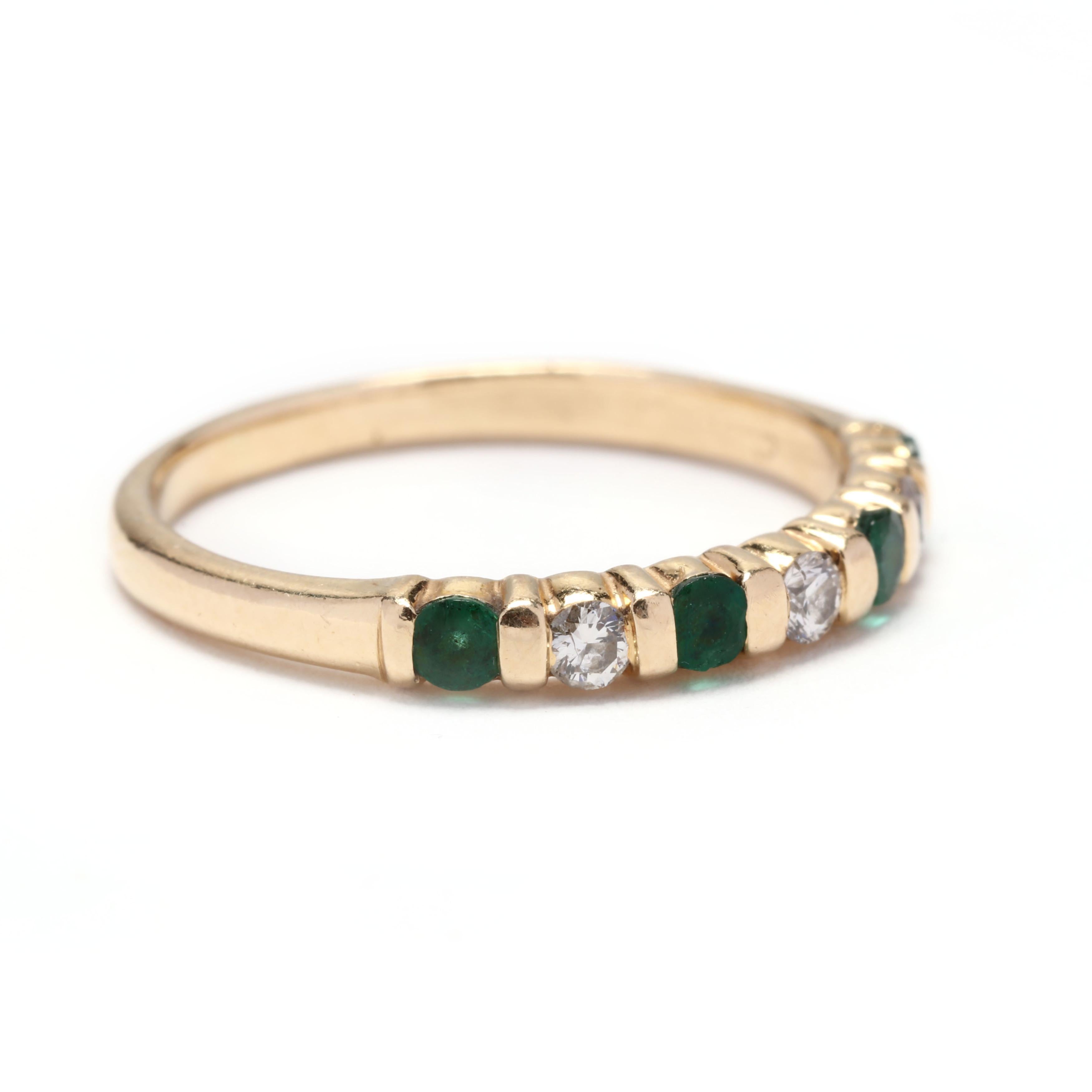 A 14 karat yellow gold, emerald and diamond stackable band ring. This ring features bar set alternating round cut emeralds weighing approximately .24 total carats and round brilliant cut diamond weighing approximately .15 total carats and a thin