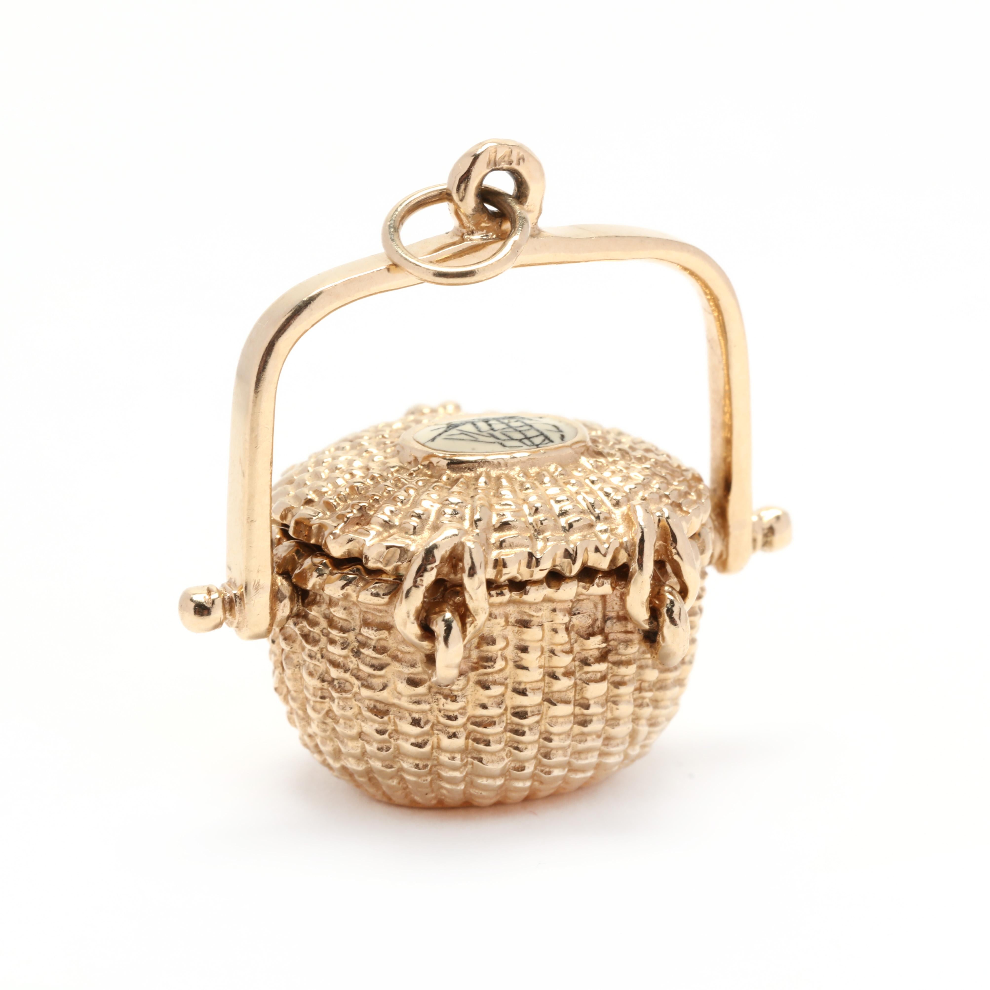 A 14 karat yellow gold Nantucket basket charm. A textured basket design with an articulated lid and an oval plaque on top depicting a ship, as well as a folding handle and designer engraving on the bottom.

Length: 1 1/4 in.

Width: 1 in.

7.1