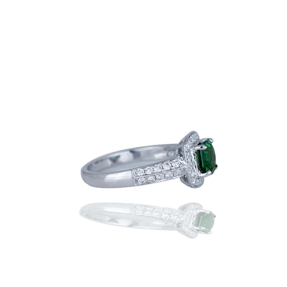 Questo anello di fidanzamento in oro bianco 14kt presenta una pietra verde con taglio a cuscino di 6 mm circondata da un'aureola di 0,40 carati di diamanti di purezza VS e colore F incastonati con una precisa tecnica di micro pave. La pietra verde