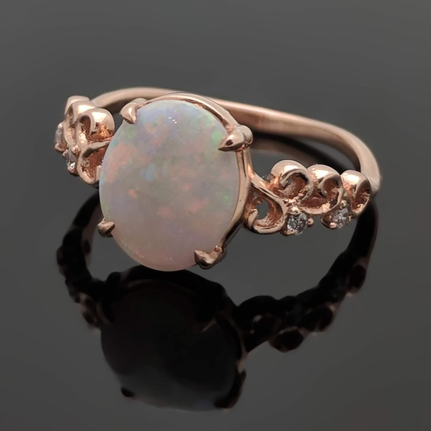 A 14kt rose gold ring set with an Australian Opal at an estimated weight of 1ct in a 4 prong setting featuring carved details and accented diamonds estimated at 0.02 cttw.  Estimated weight of gold is 1.5 gr. 

We will size it for you.

